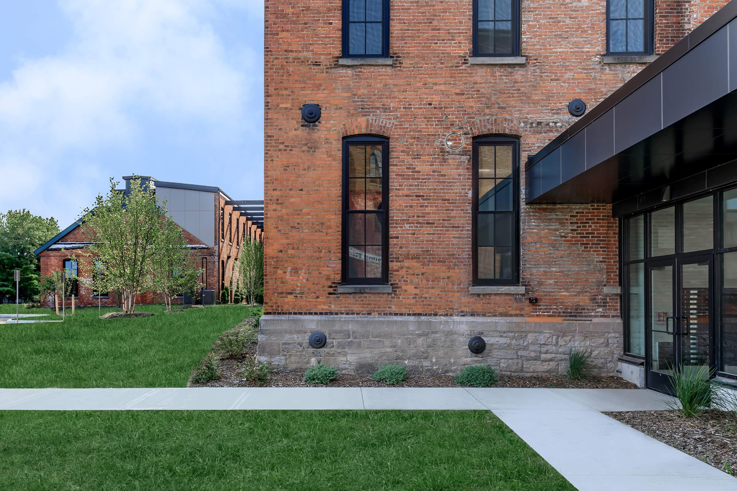 a large brick building with grass in front of a house