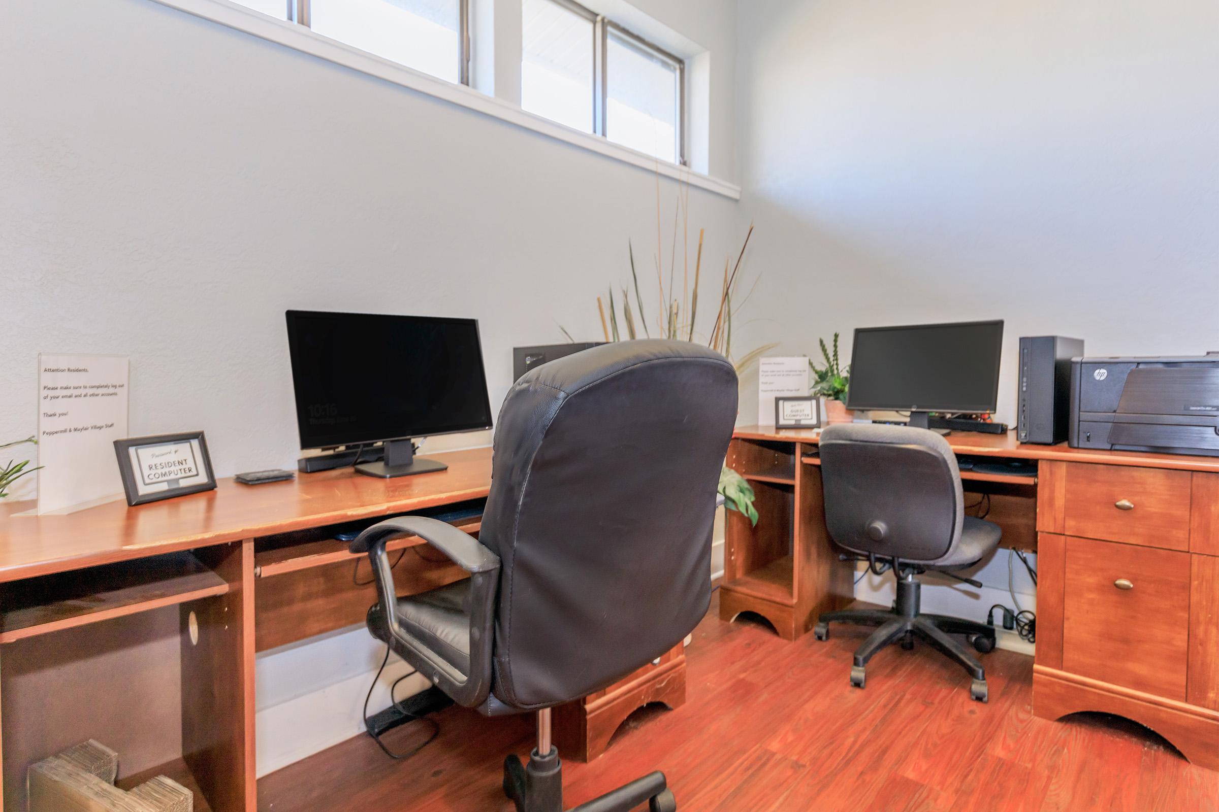 a desk with a computer and a chair in a room