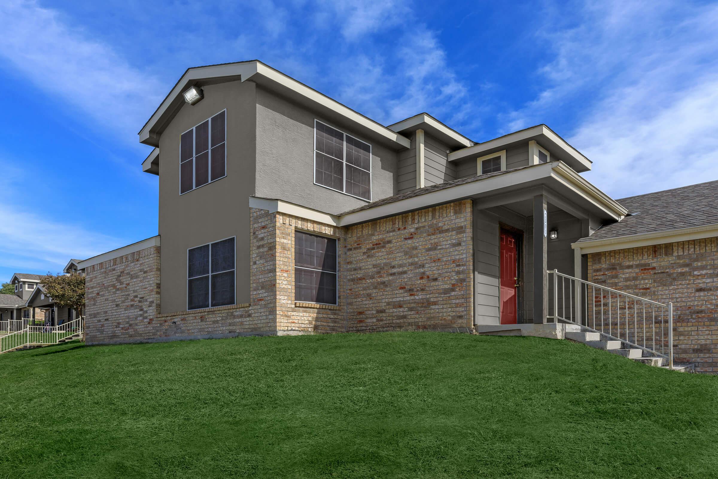 a large brick building with grass in front of a house