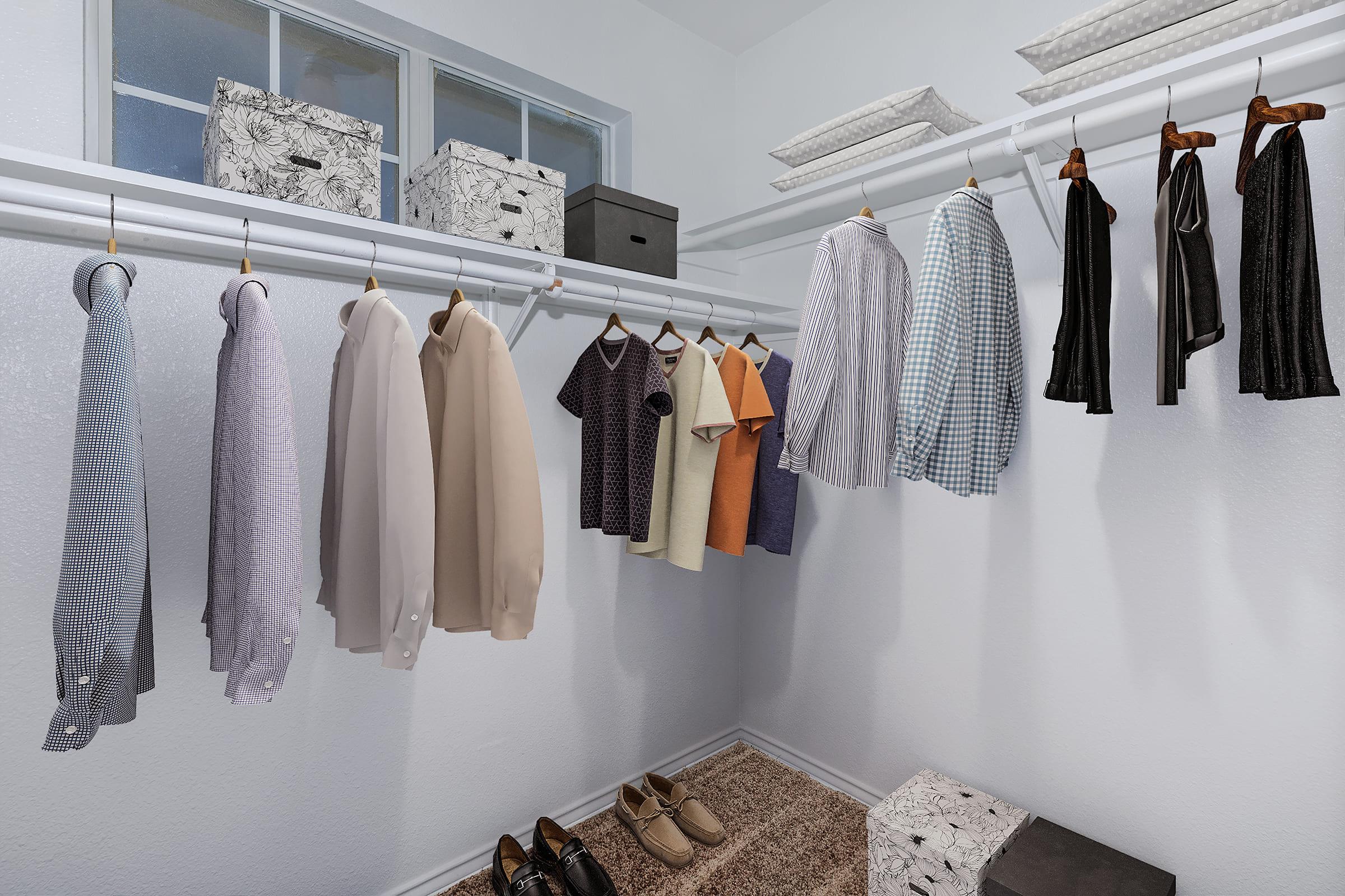 A well-organized closet featuring a variety of shirts, including dress and casual styles, hanging on white hangers. Two pairs of dress shoes are placed on a soft rug at the bottom. Adjacent to the clothes, patterned storage boxes are neatly arranged on the shelf above.