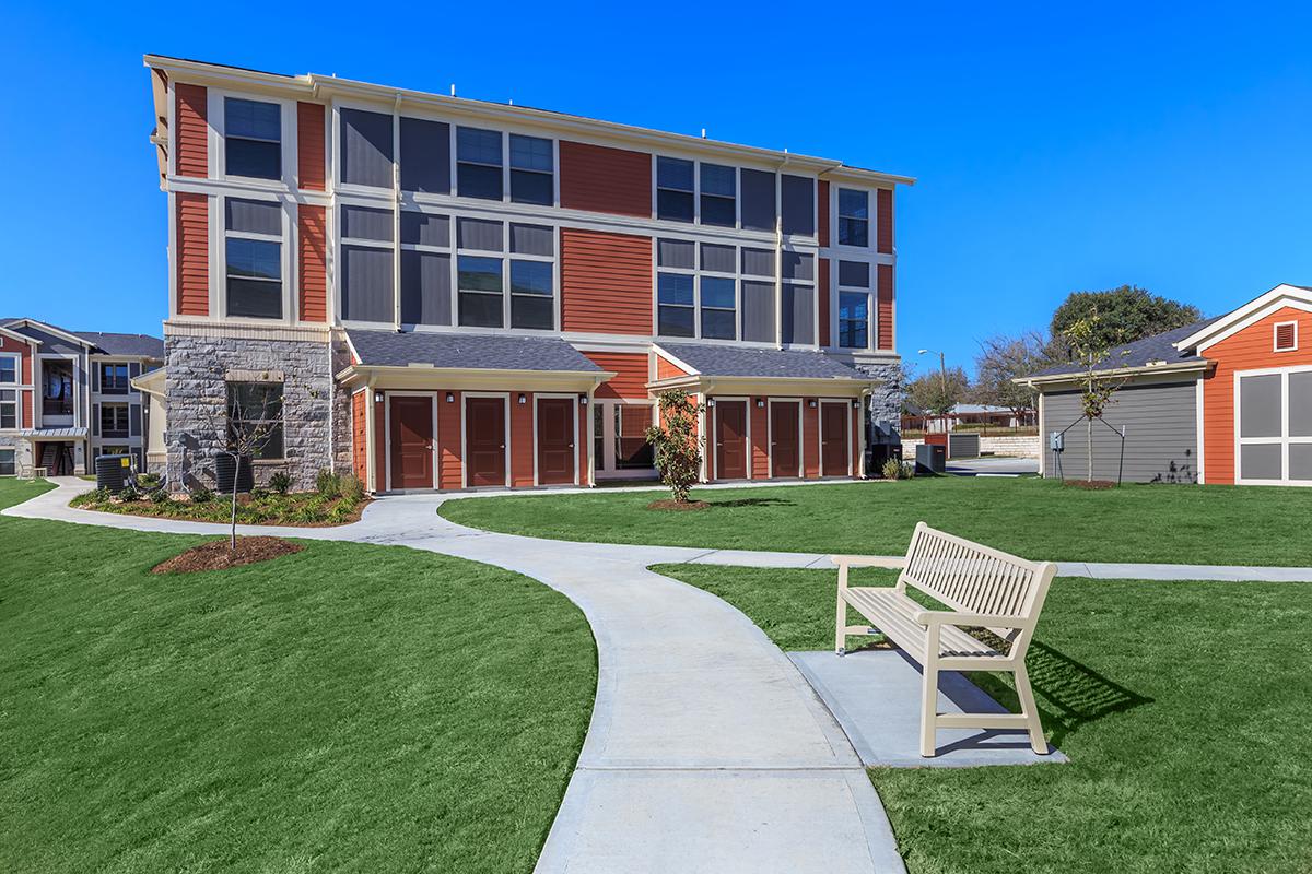 a house with a lawn in front of a brick building