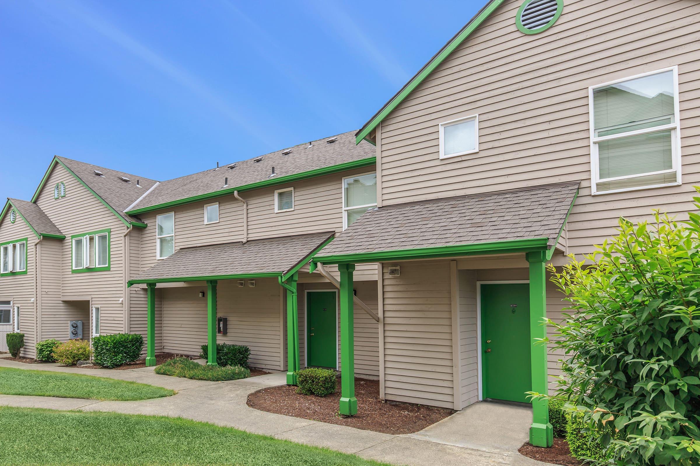 A row of contemporary two-story townhouses with light brown siding and green accents.