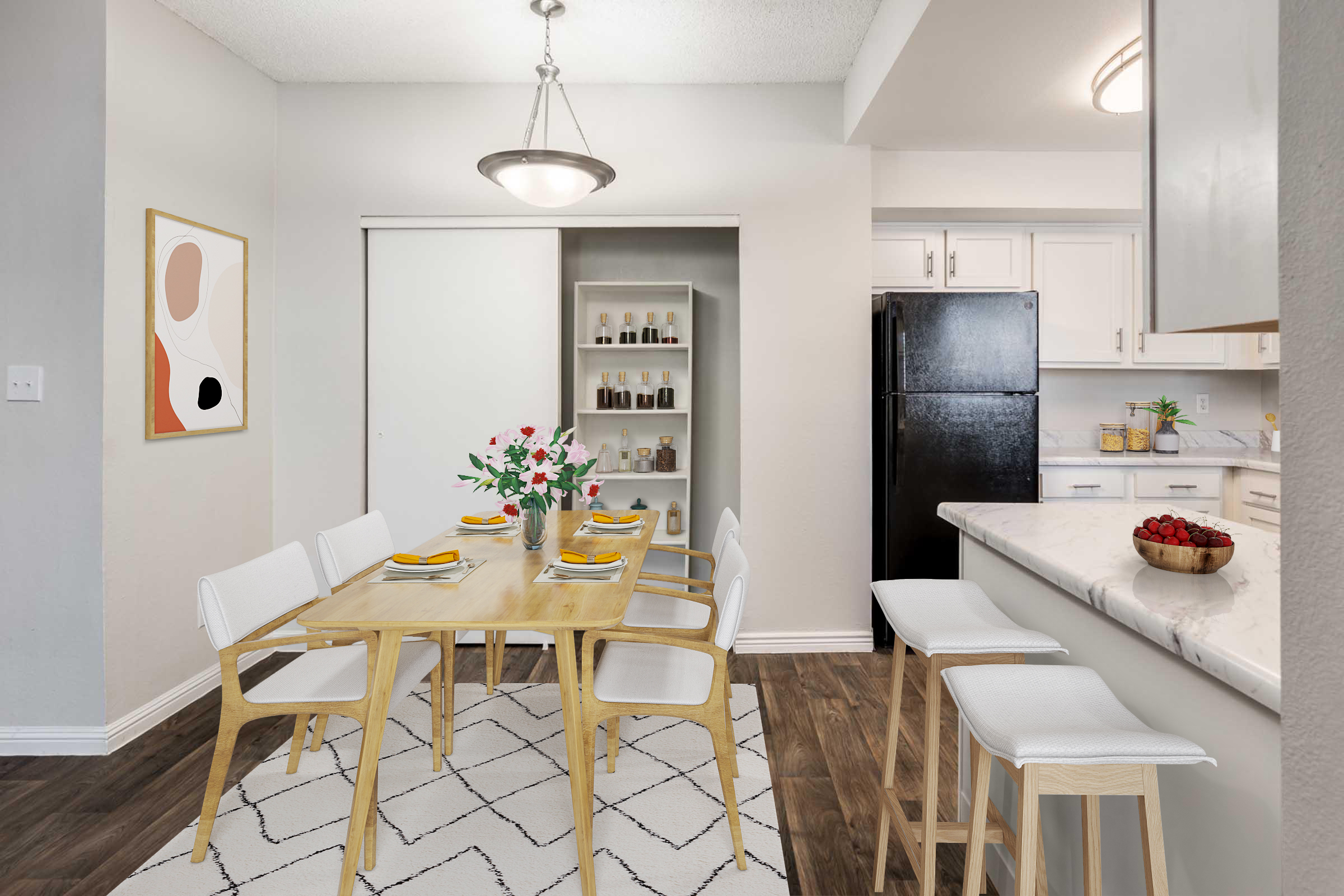 Bright and modern dining area featuring a wooden table set for four with yellow placemats, white chairs, and a vase of flowers. A small kitchen bar with stools is visible, along with a black refrigerator and light-colored cabinetry. The decor includes a framed abstract artwork on the wall.
