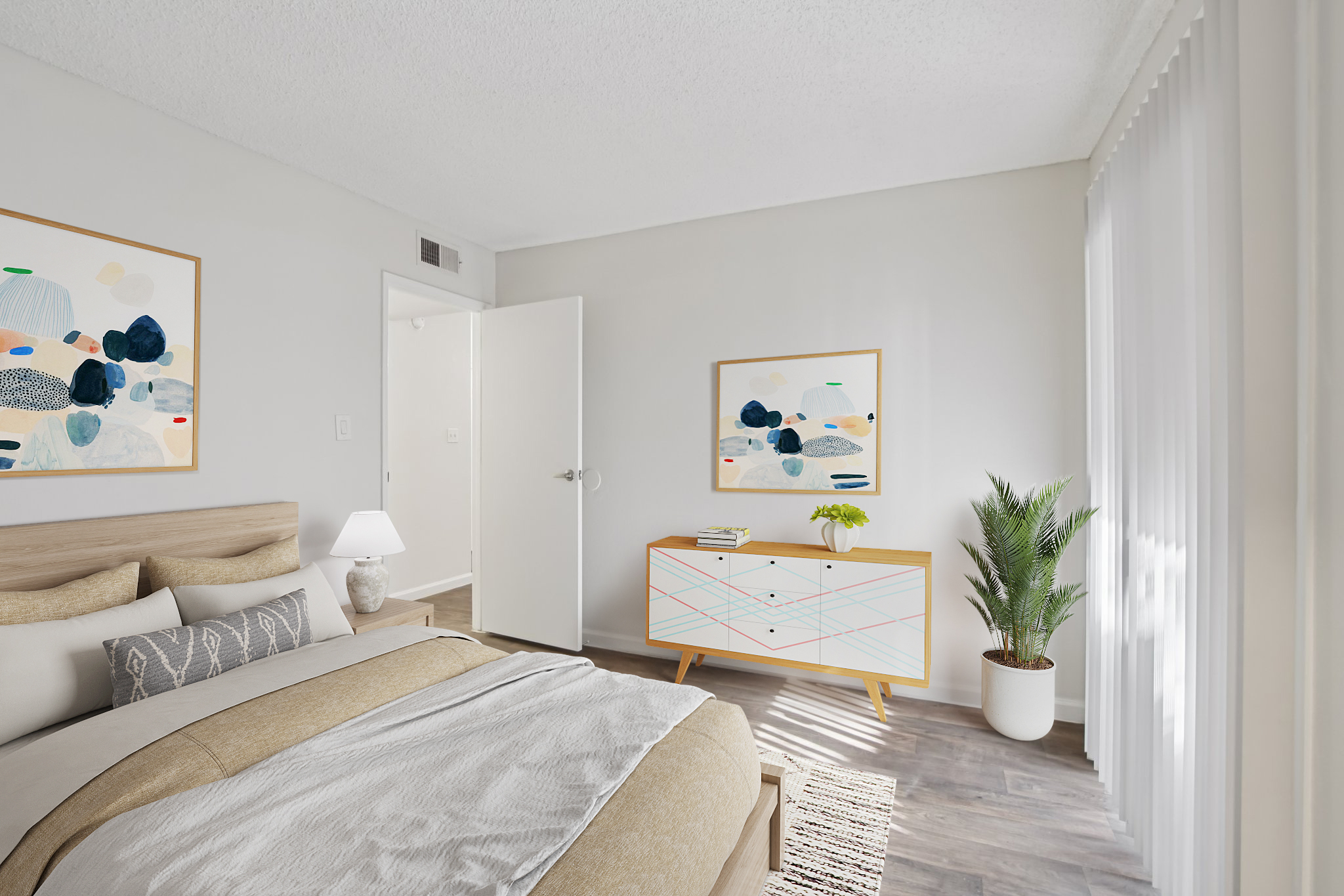 A cozy modern bedroom featuring a neatly made bed with light-colored bedding, a bedside lamp, and framed artwork on the walls. A stylish dresser with decorative items and a potted plant are visible, alongside a large window with light-filtering curtains, enhancing the bright and inviting atmosphere.