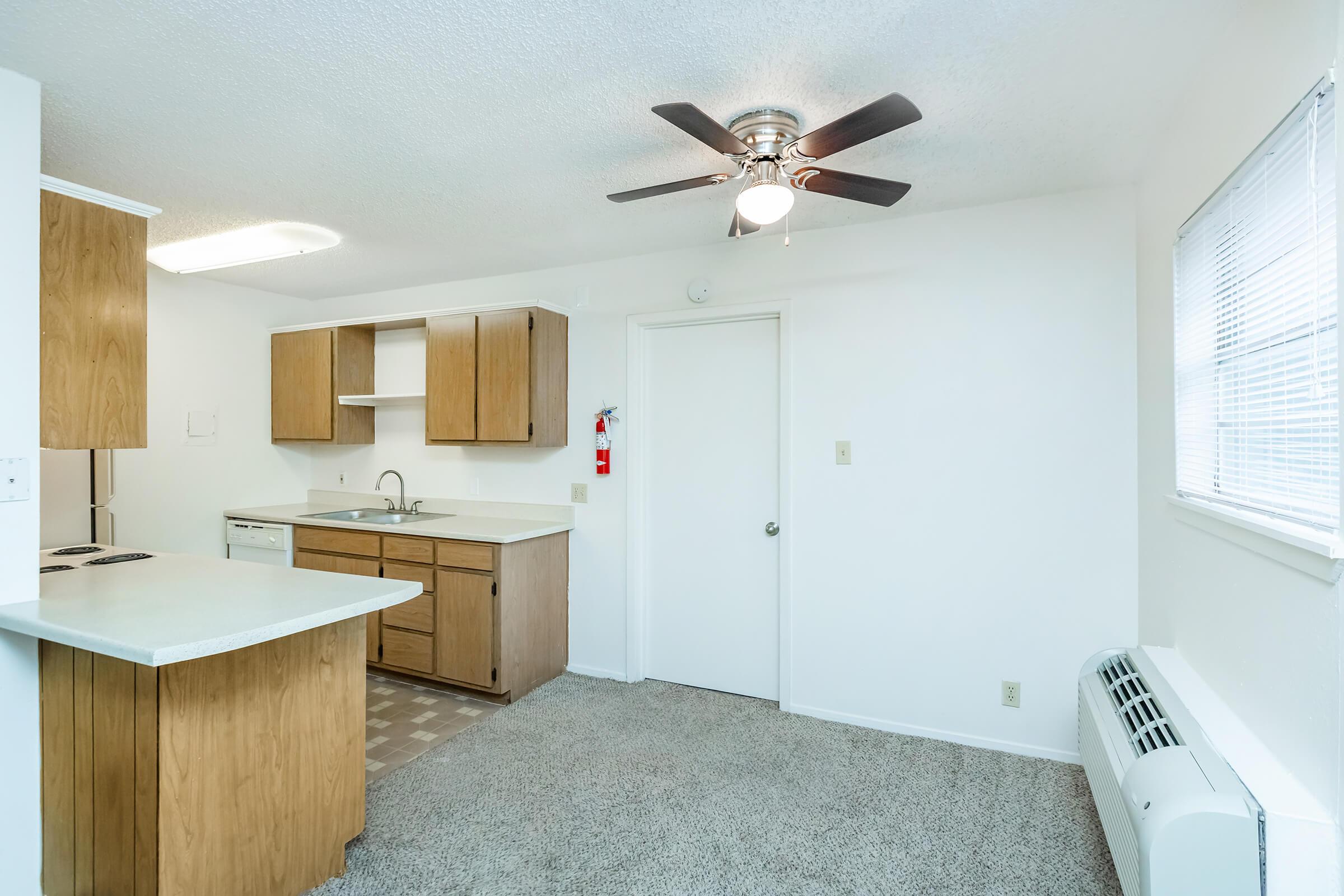 a kitchen with wooden cabinets and a bed in a room