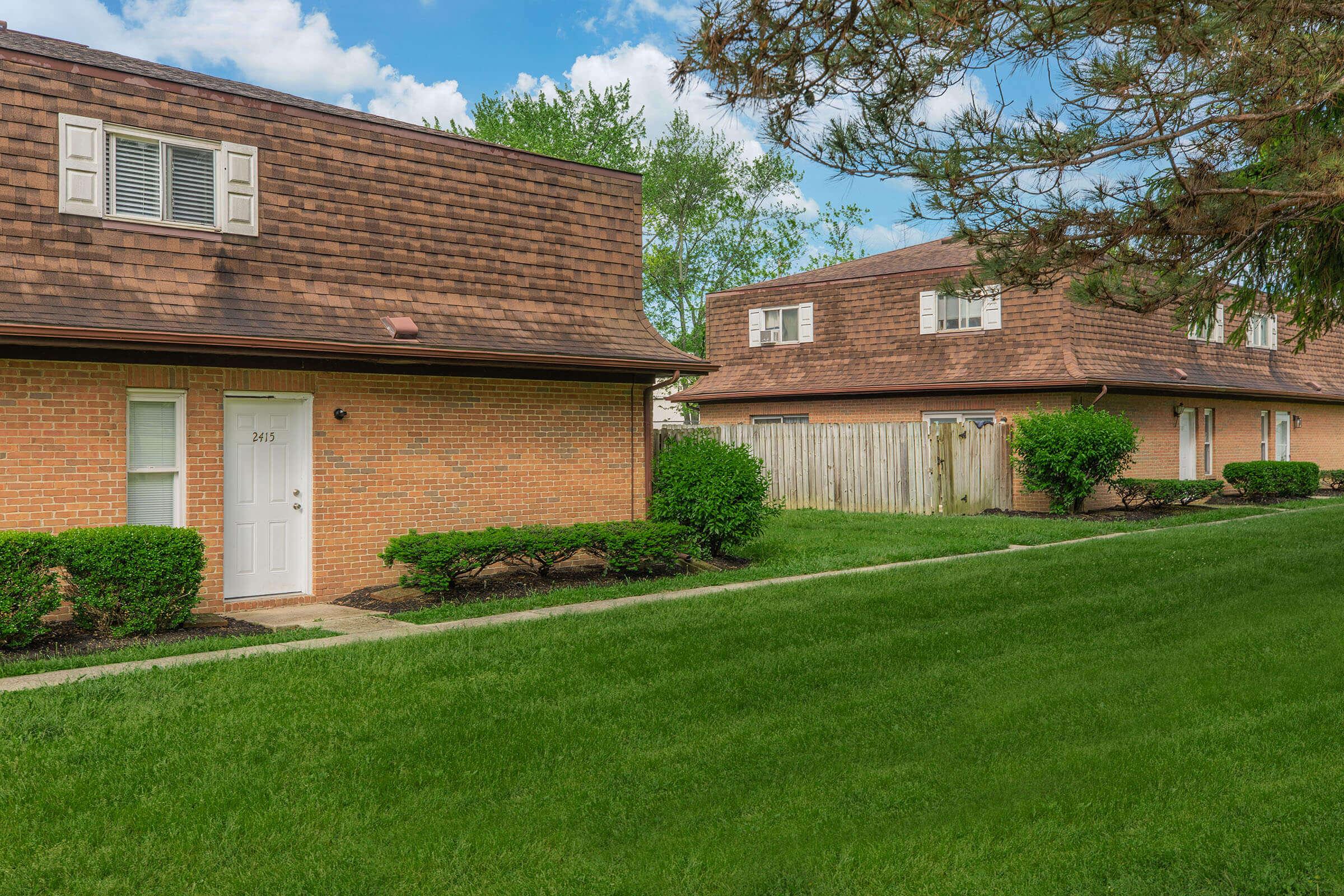 a large brick building with grass in front of a house