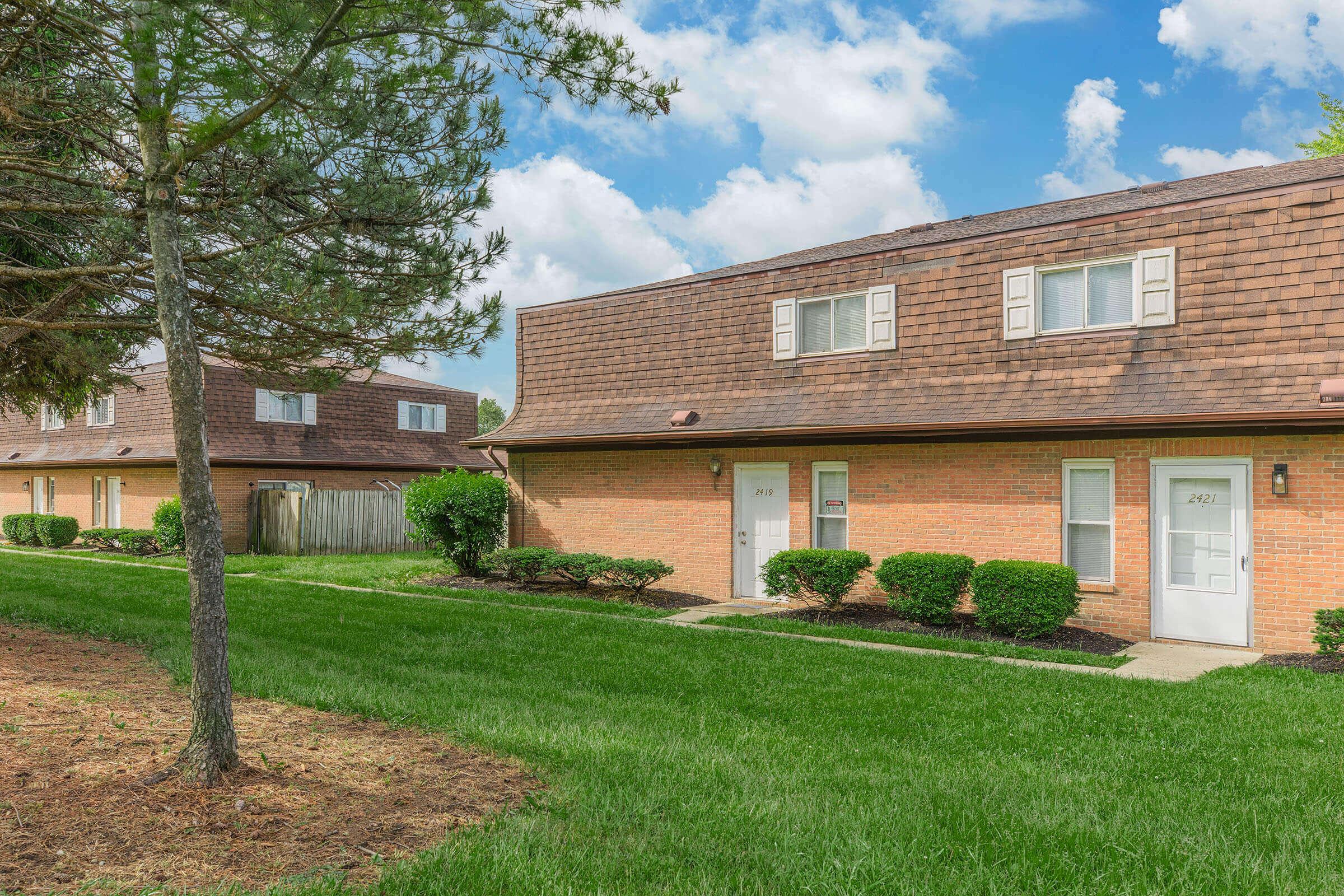 a large brick building with grass in front of a house