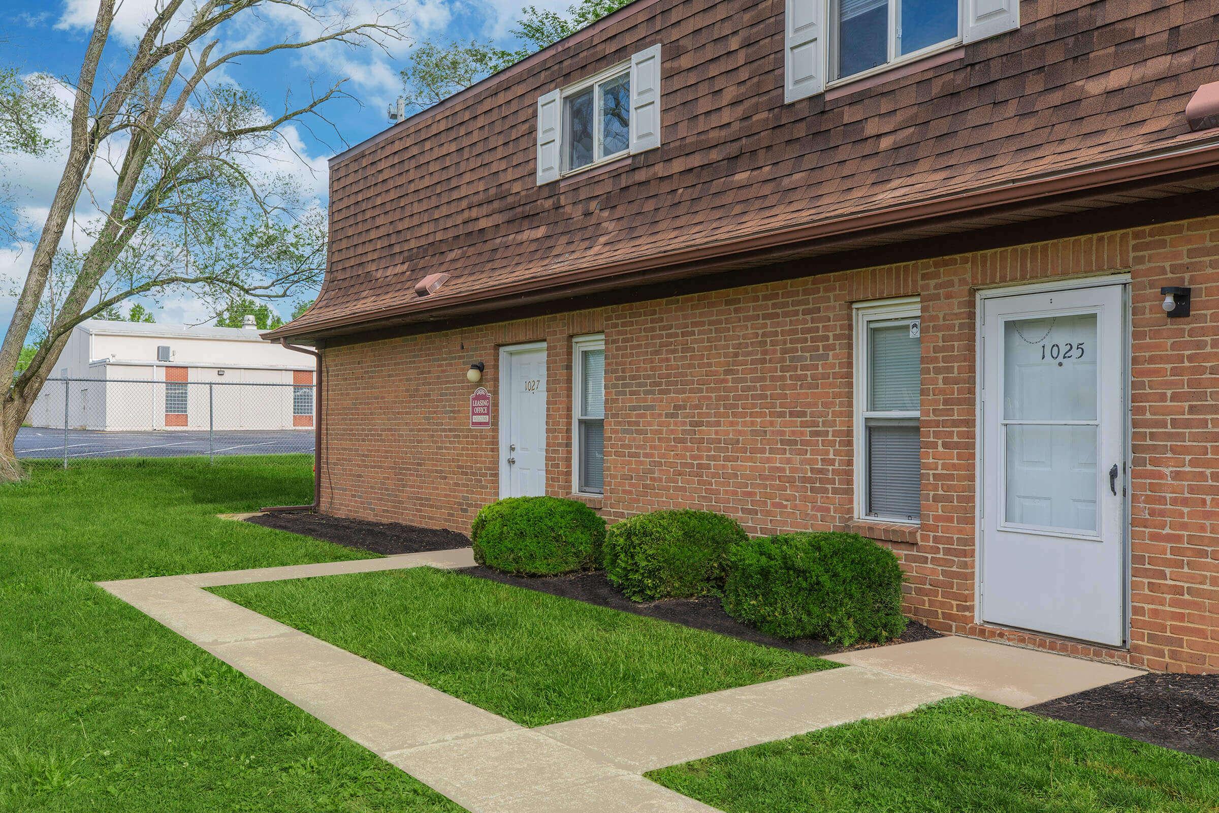 a large brick building with grass in front of a house