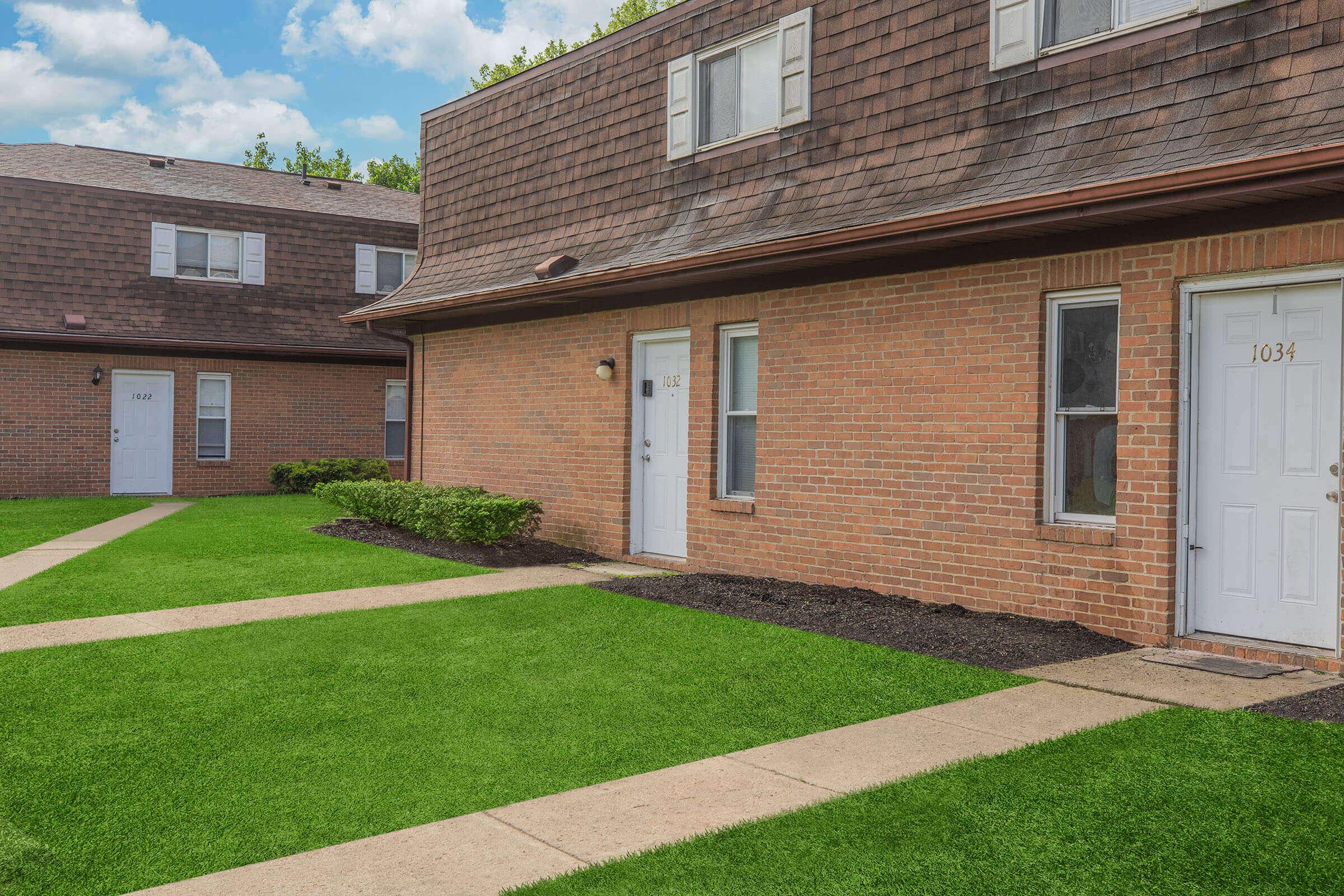 a large brick building with grass in front of a house