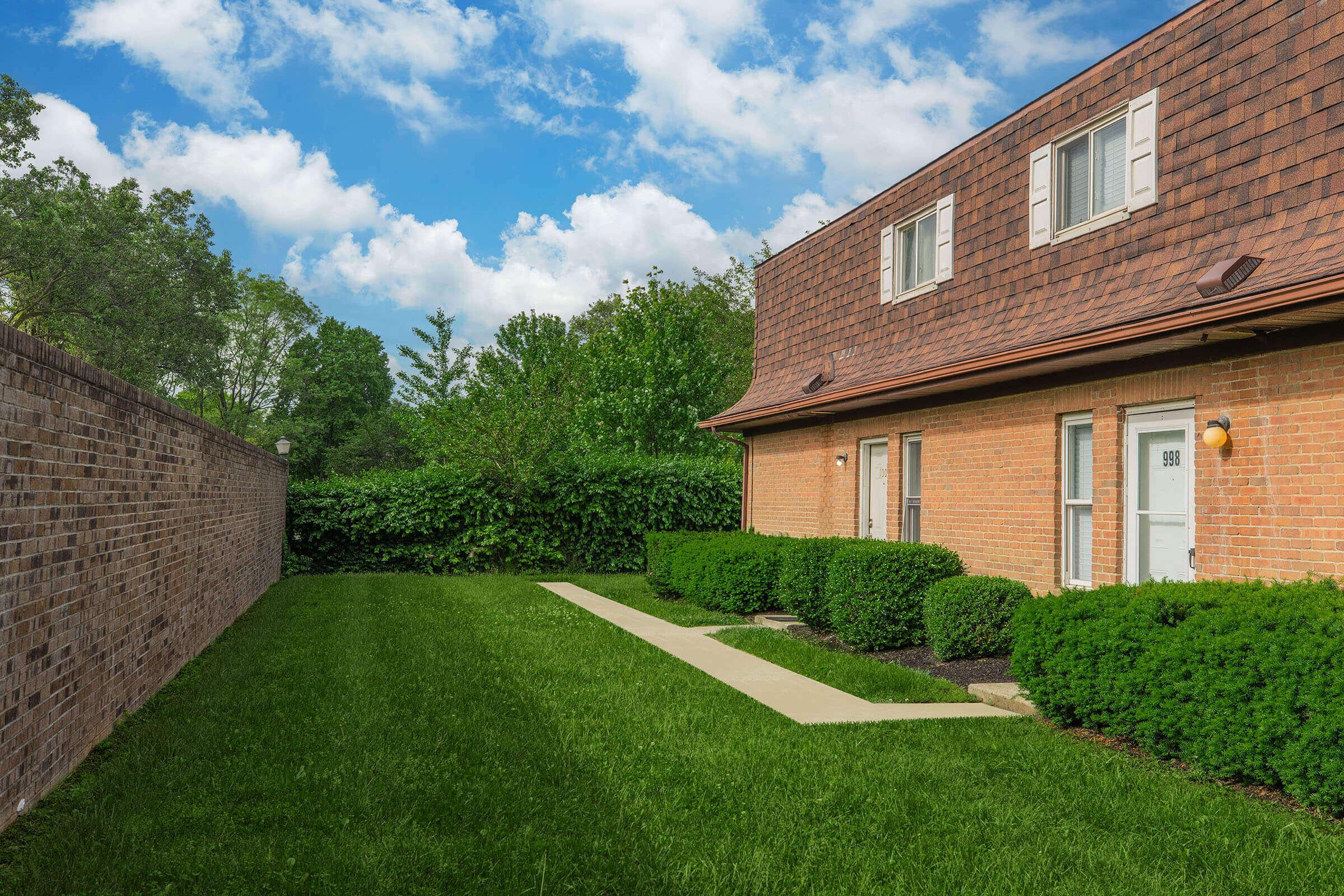 a large brick building with grass in front of a house