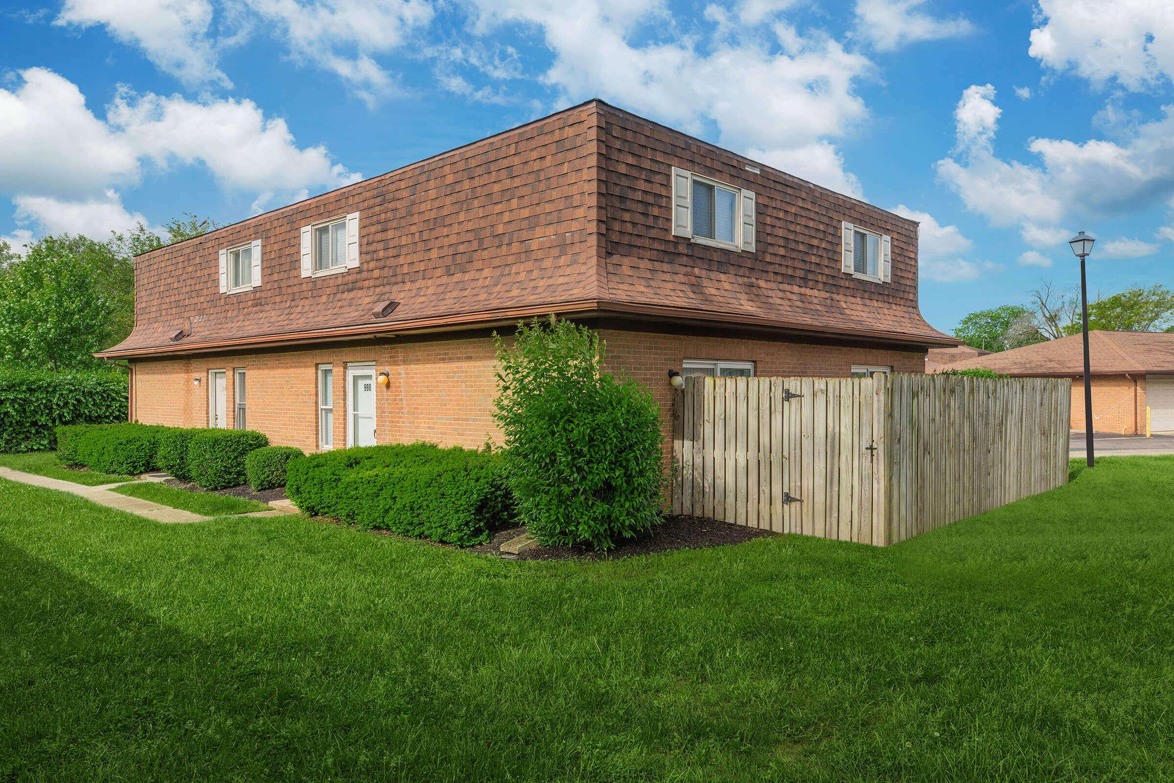 a large brick building with grass in front of a house