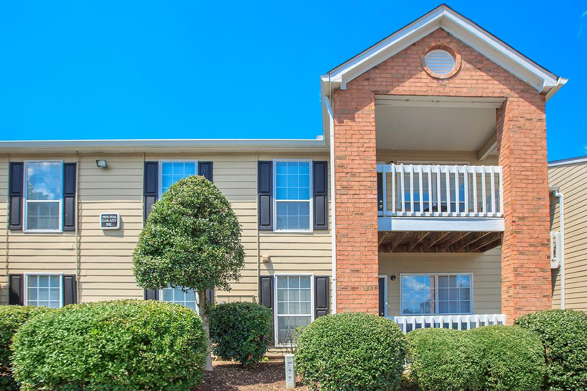 a house with bushes in front of a brick building
