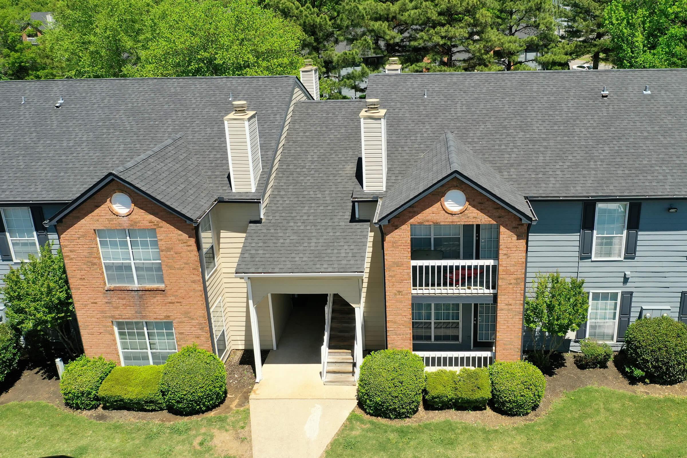 a large brick building with green grass in front of a house