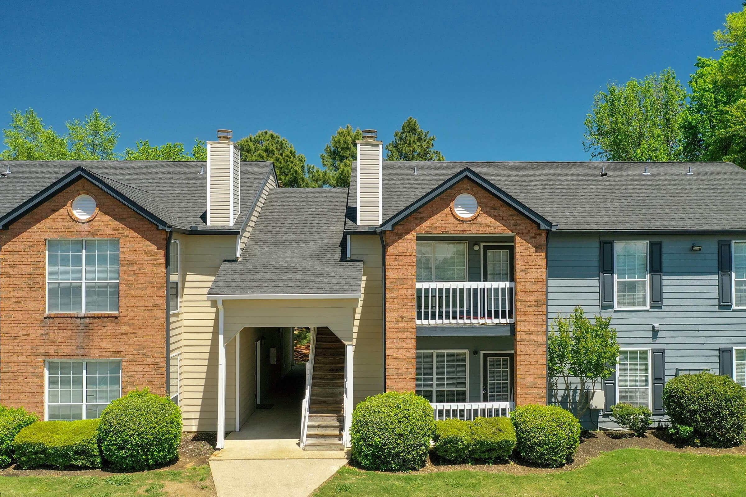a house with bushes in front of a brick building