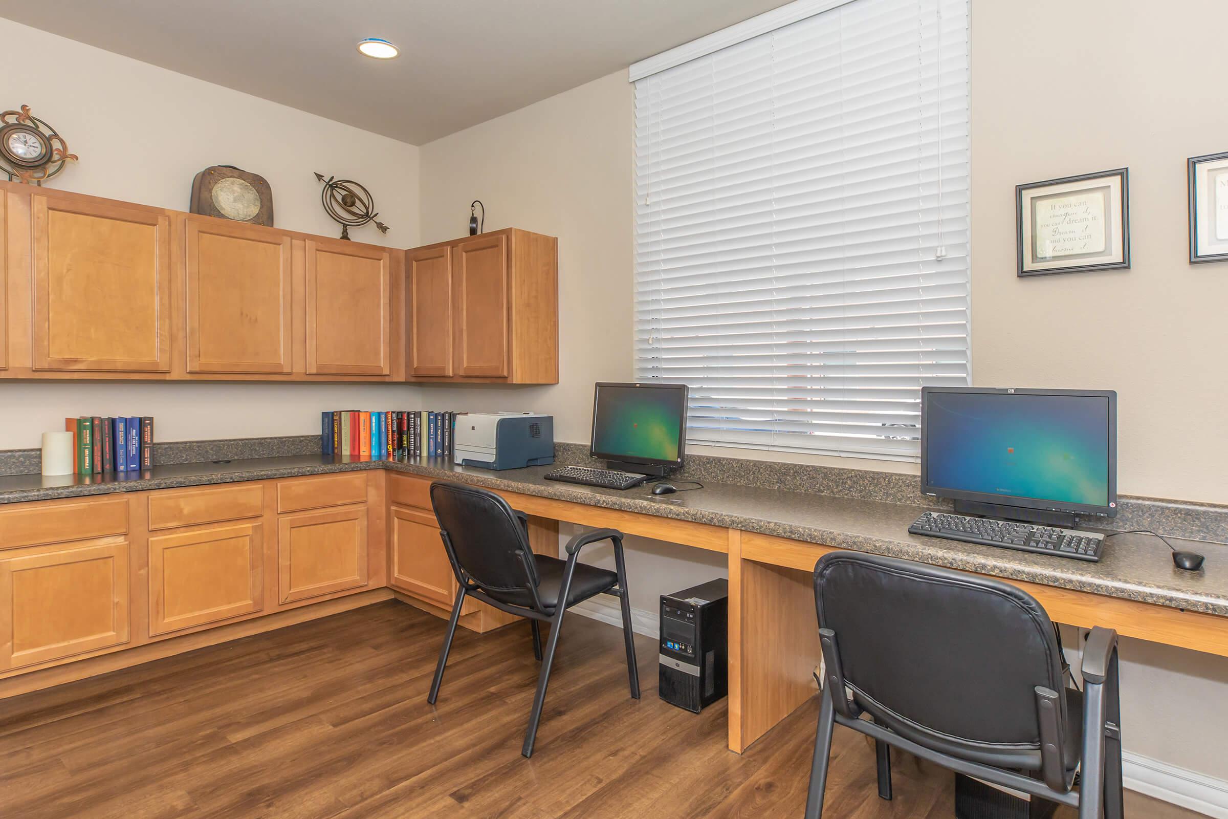 a desk with a computer and a chair in a room