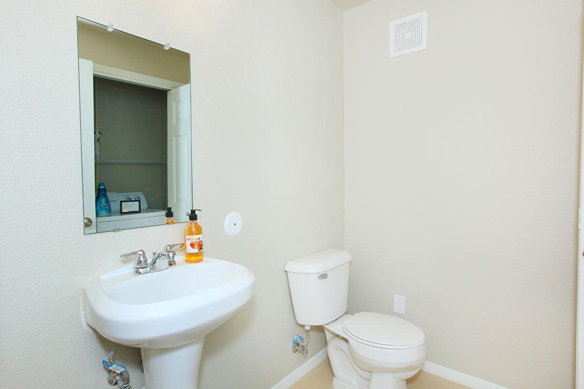 a white sink sitting under a mirror