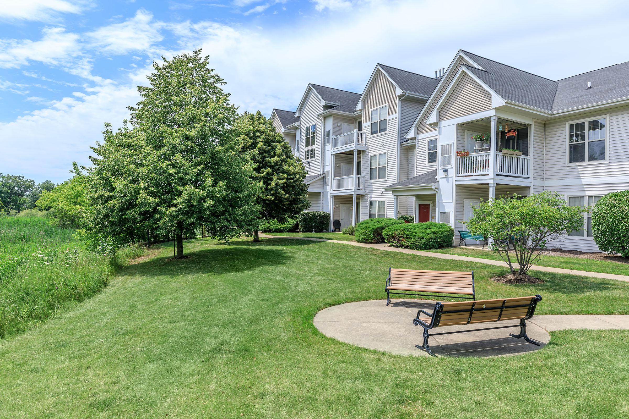 a wooden park bench sitting in front of a house