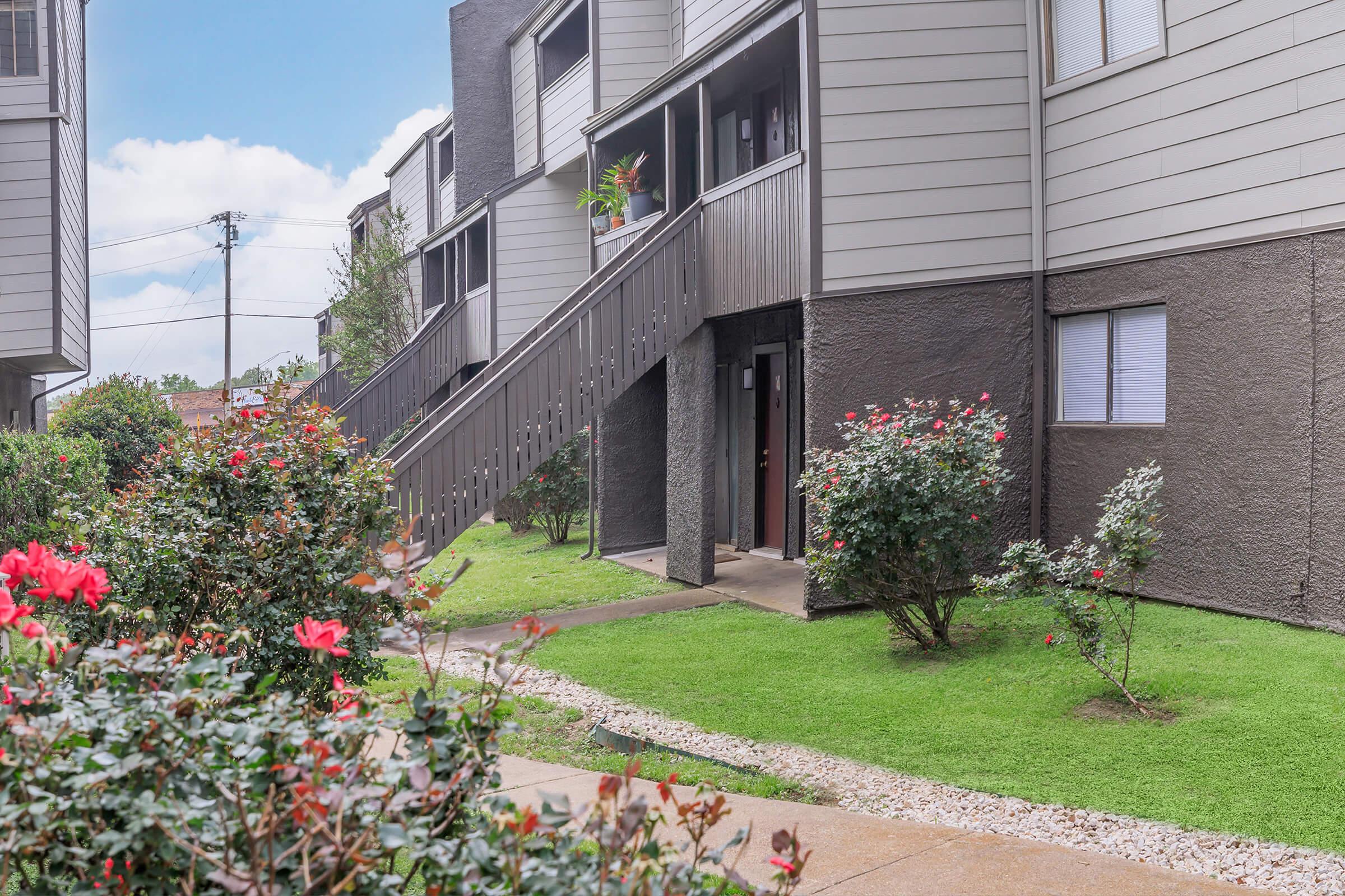 a close up of a flower garden in front of a brick building