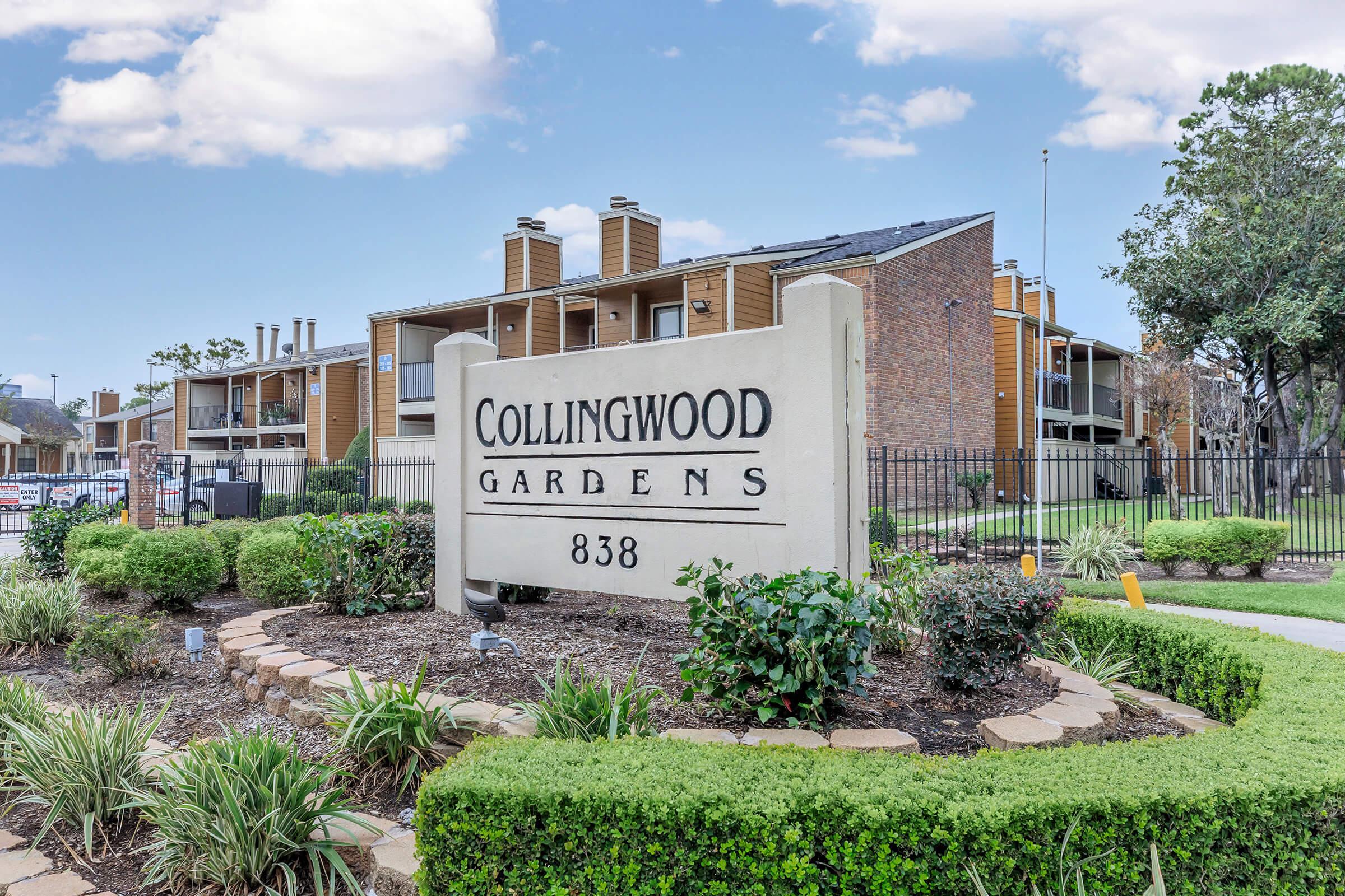 Sign for Collingwood Gardens at 838, featuring a landscaped entry with shrubs and small trees. The background shows an apartment building with a blue sky and a few clouds above. The area is well-maintained, creating a welcoming atmosphere for residents.