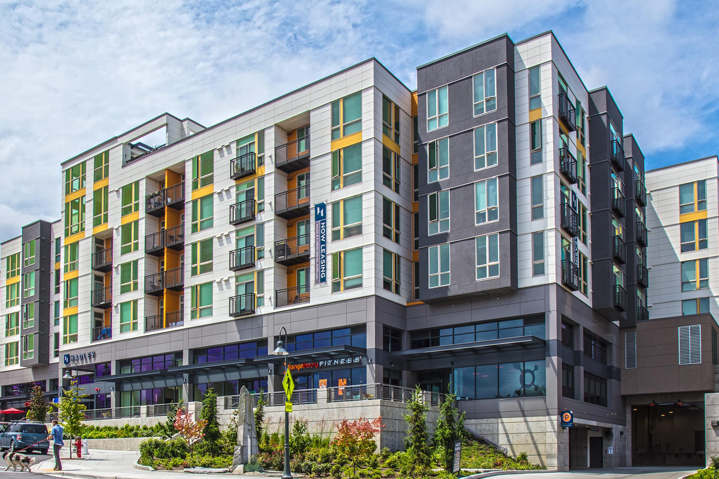 Modern multi-story apartment building with a mix of gray, green, and yellow exterior.