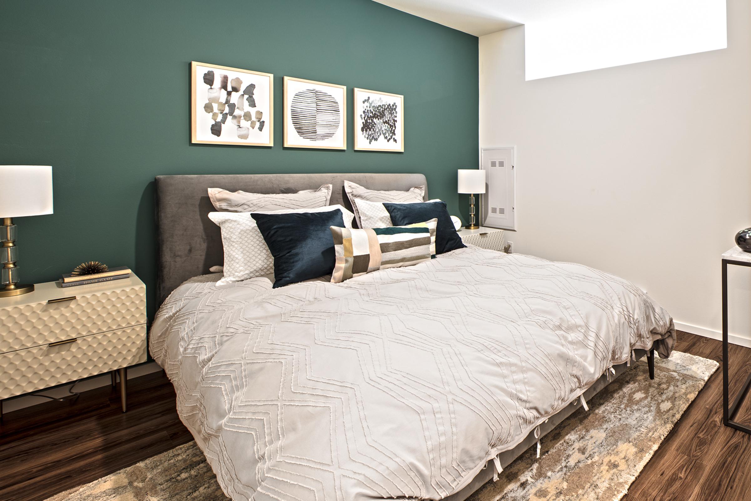 A modern bedroom featuring a queen-sized bed with a gray comforter and decorative pillows.