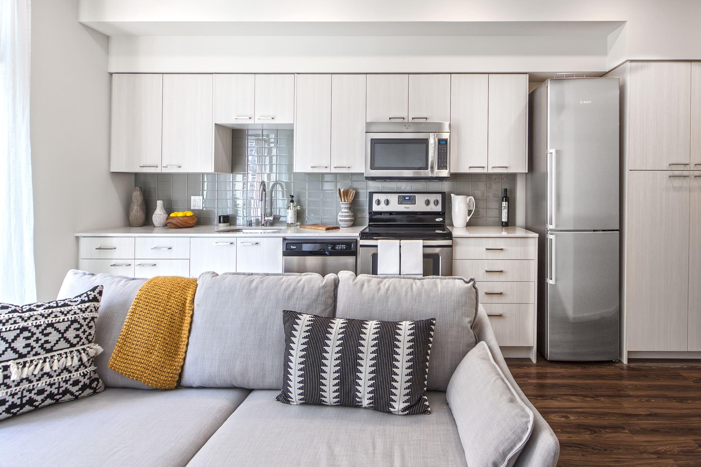 Modern kitchen featuring stainless steel appliances, including a microwave and refrigerator, with light-colored cabinetry.