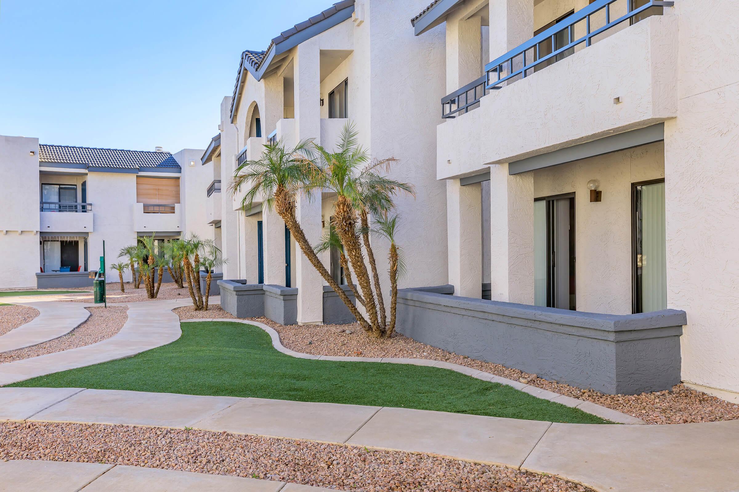 Outside view of the Rise on Cactus apartments with walkways, gravel and grass in front of them