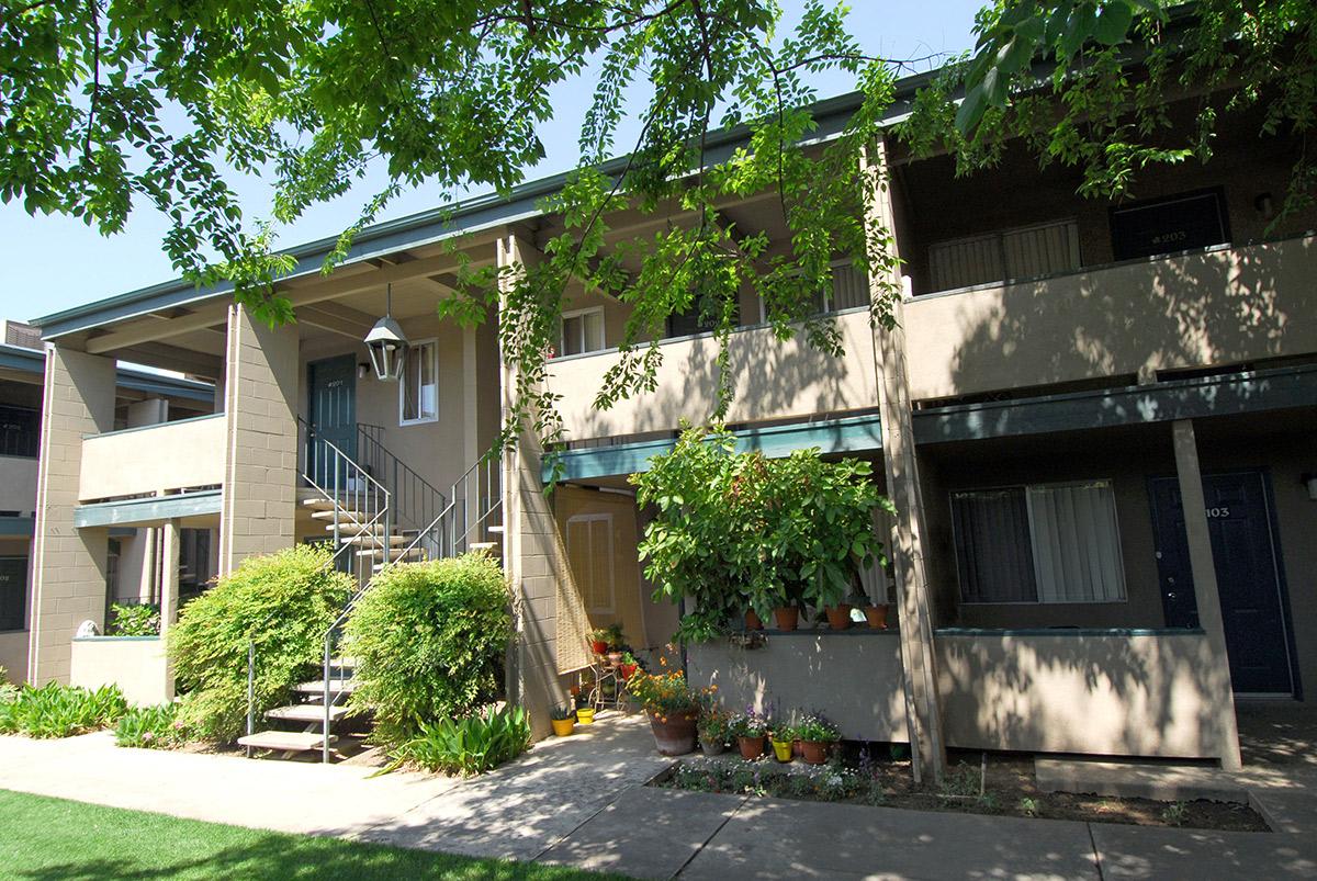 a house with bushes in front of a brick building