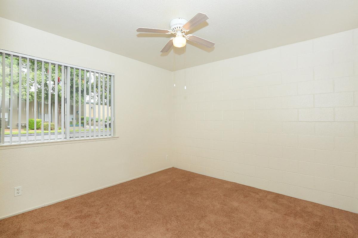 carpeted floor in bedroom with a ceiling fan and window.