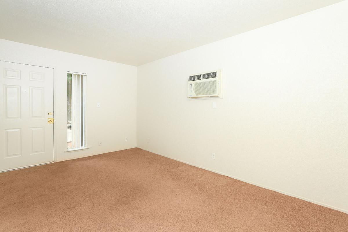 carpeted living room with door and air conditioner.