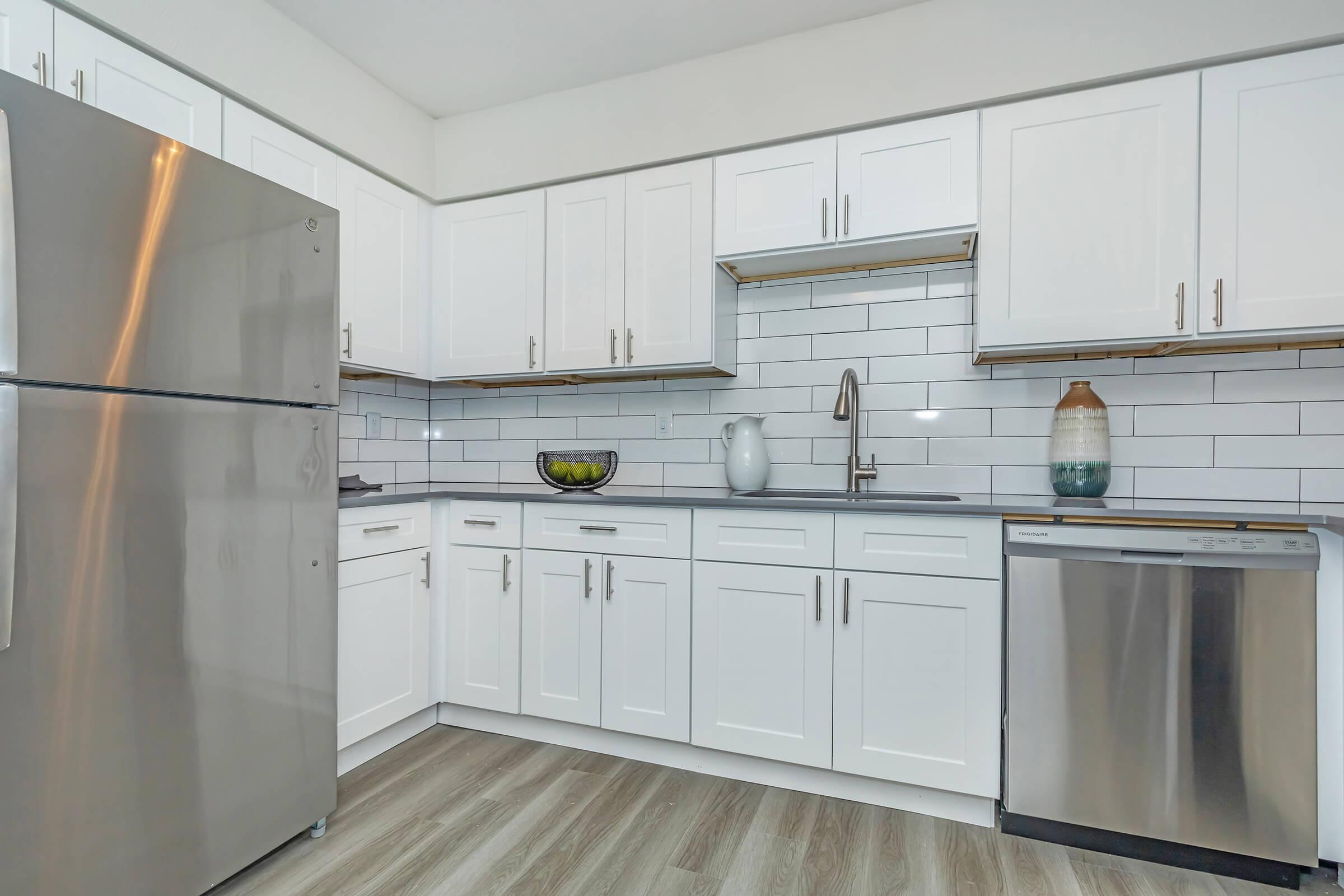 Luxury Apartments in Phoenix, AZ - Tides on 71st - Kitchen with White Cabinetry, Stainless Steel Silver Appliances, and Decorative Vases