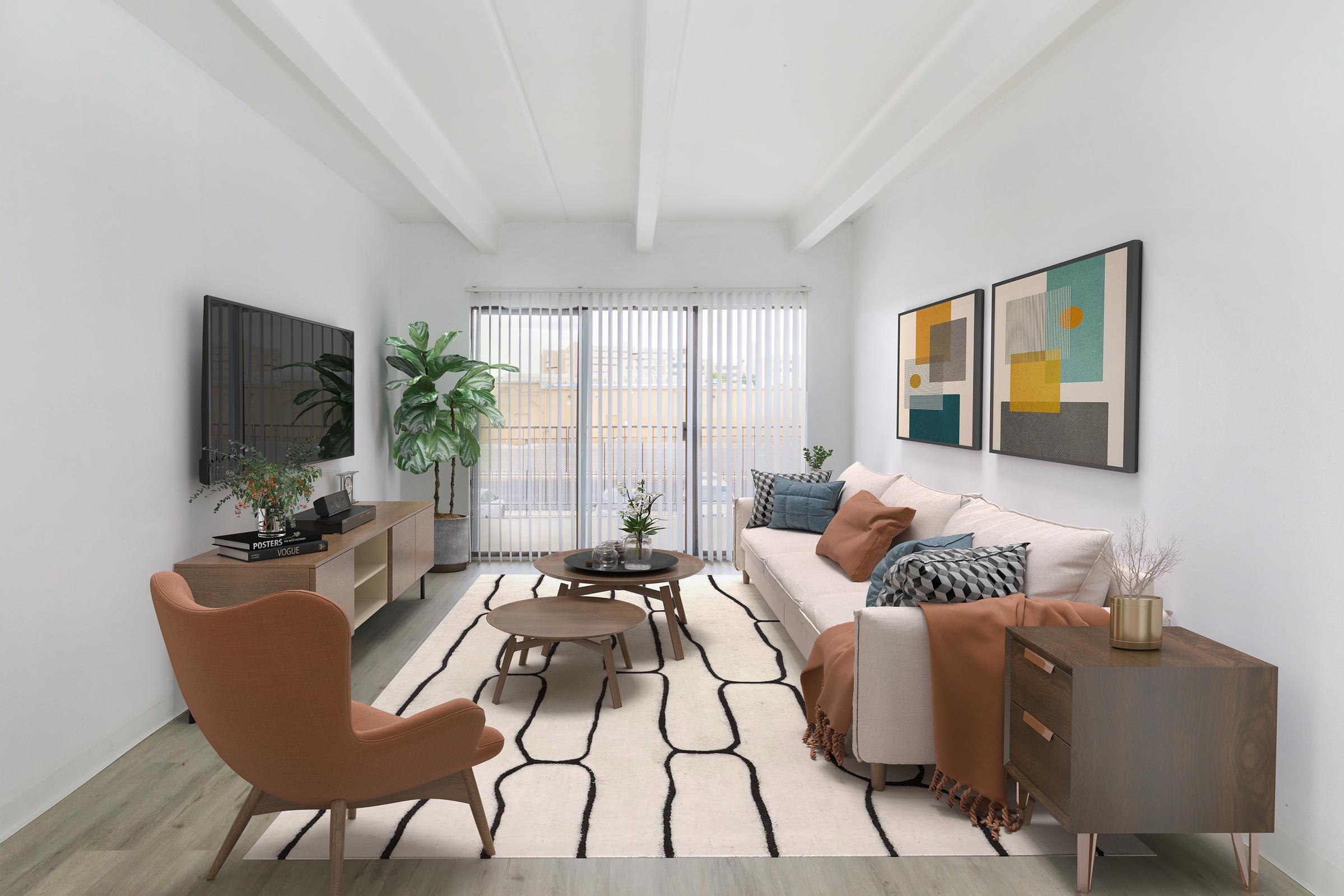 A modern living room featuring a white sofa adorned with orange and brown pillows, an orange armchair, and a wooden coffee table on a cream-colored area rug. The space includes a large television on a media console, decorative plants, and abstract artwork on the walls, with natural light streaming through window blinds.