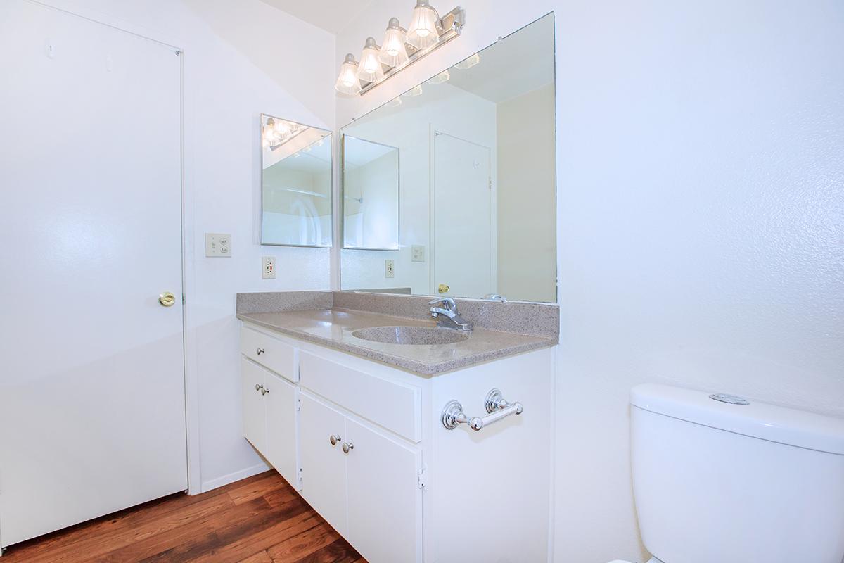 a white sink sitting under a mirror