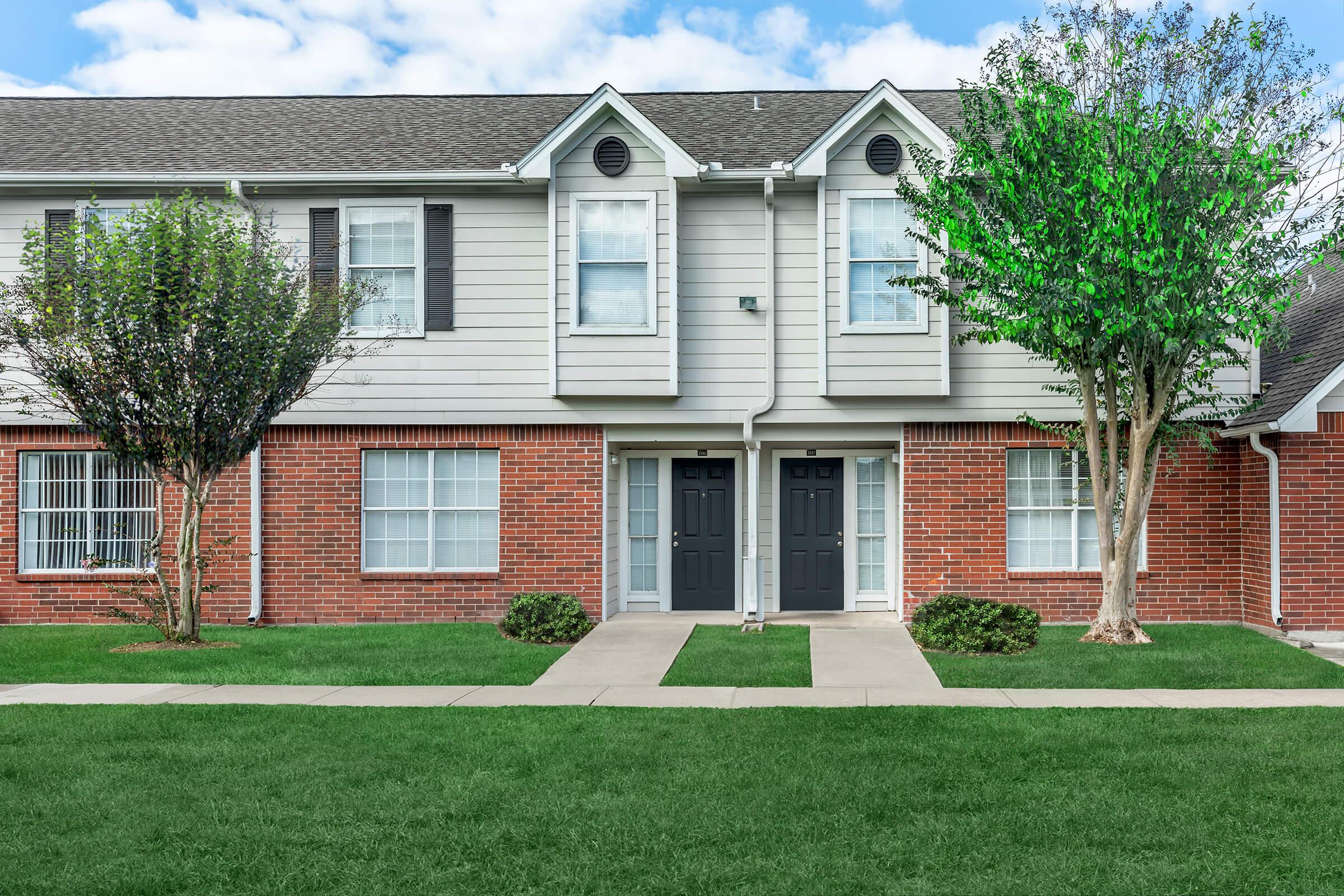 a house with a lawn in front of a brick building