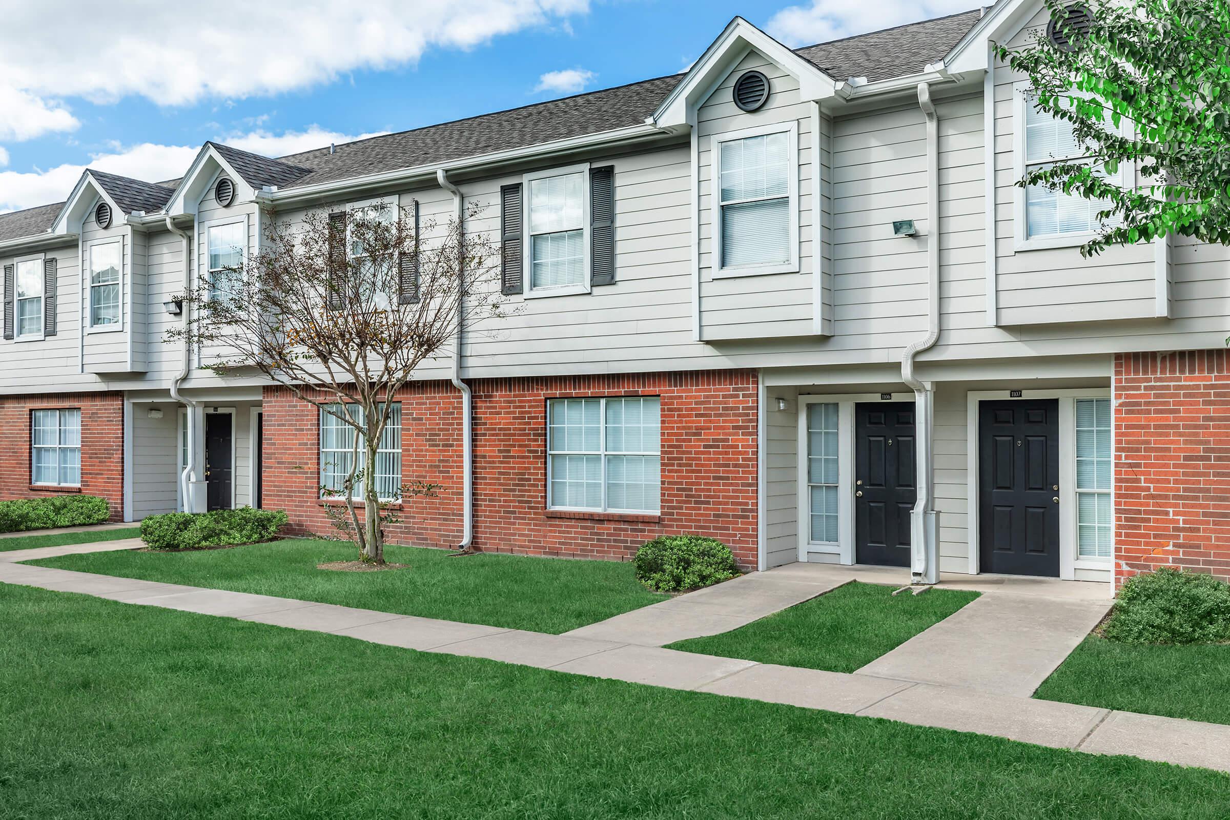 a house with a lawn in front of a brick building