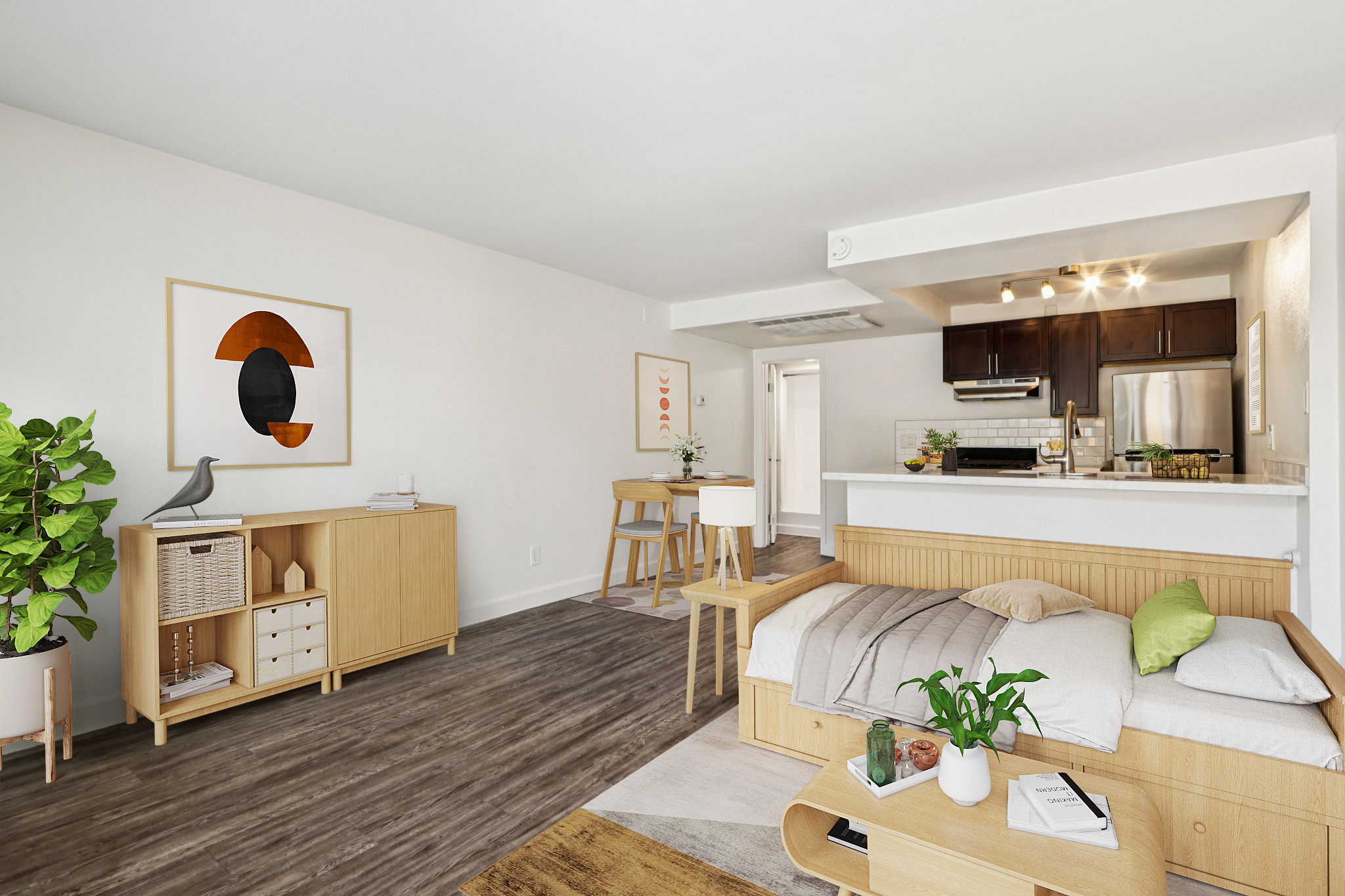 A modern, minimalist living space featuring light wood furniture. The room includes a cozy bed, a wooden storage unit, and a dining table. Large windows allow natural light, complemented by green plants and contemporary artwork on the walls. The kitchen area is open, showcasing dark cabinetry and stainless steel appliances.