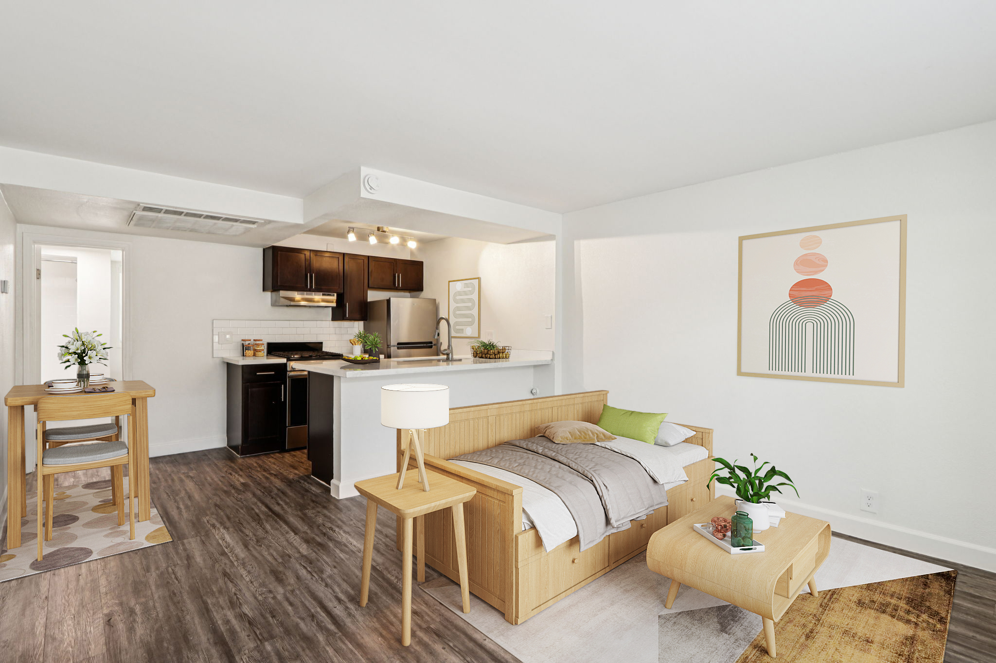 Bright and modern living space featuring a cozy sofa bed, a small dining table, and a stylish lamp. The kitchen area is neatly designed with dark cabinets and stainless steel appliances. Light-colored walls and natural wood accents create an inviting atmosphere, complemented by minimalist wall art.