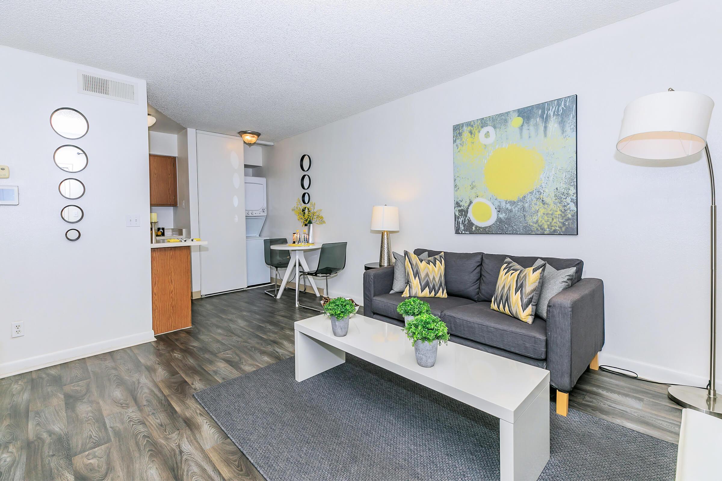 A cozy apartment with wood-style floors, a couch and dining area at Rise North Ridge.
