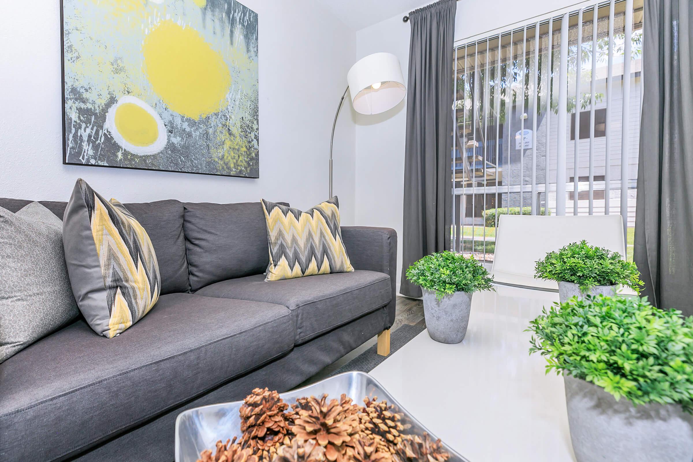 A grey couch with colorful pillows in a living room with sliding doors at Rise North Ridge.