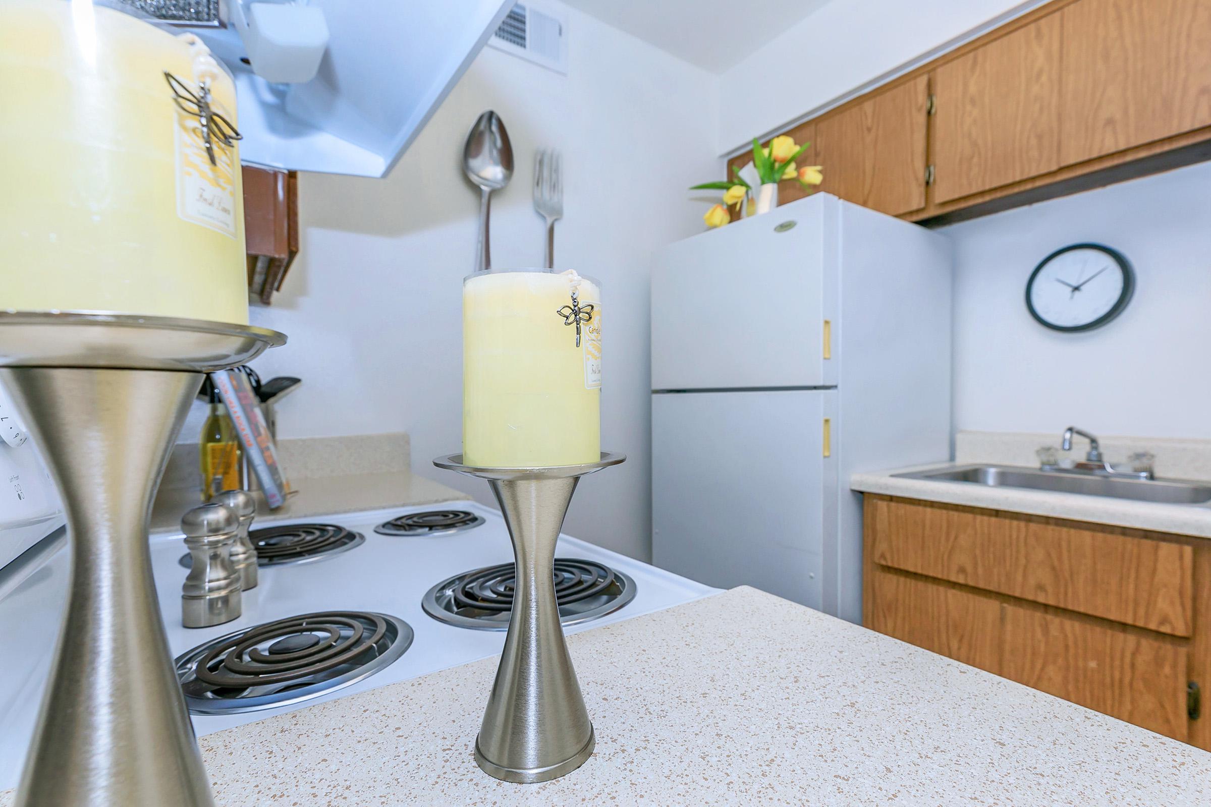 Candles in a kitchen with wood cabinets and a fridge at Rise North Ridge.