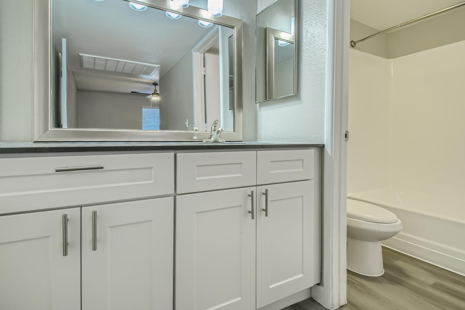 A bathroom with white cabinets and a mirror in an apartment at Rise North Ridge