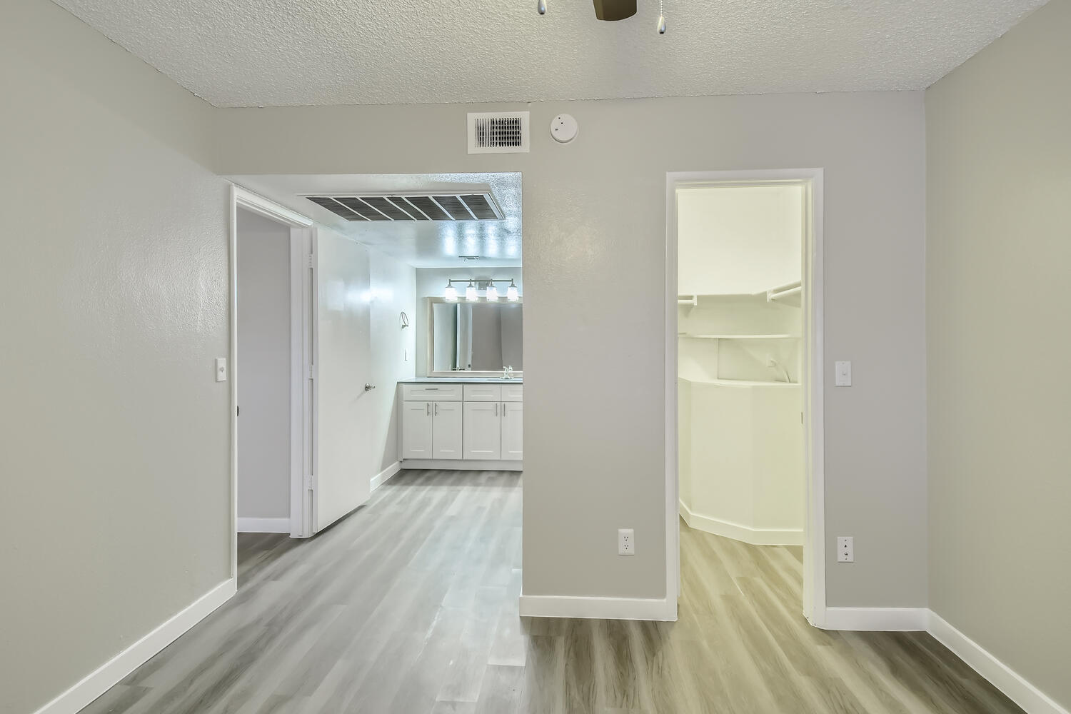 A large bedroom with wood-style flooring an en-suite bathroom and a walk-in closet at Rise North Ridge.