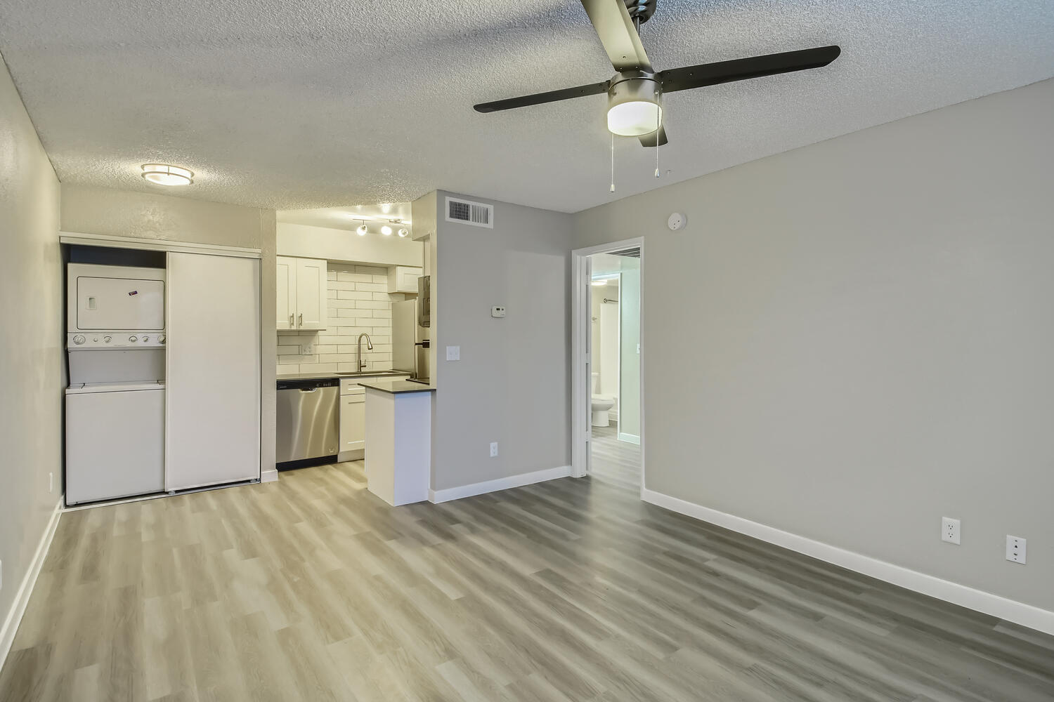 An open-concept living space with a kitchen and a closet with a washer and dryer at Rise North Ridge.