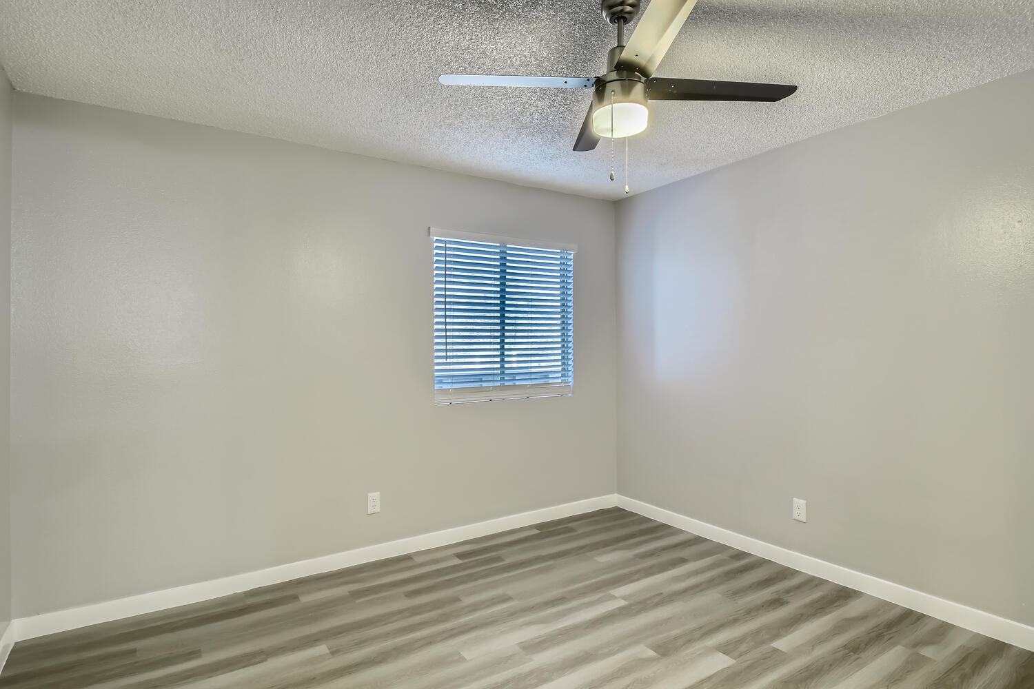A bedroom with wood-style flooring, a ceiling fan, and a window at Rise North Ridge.