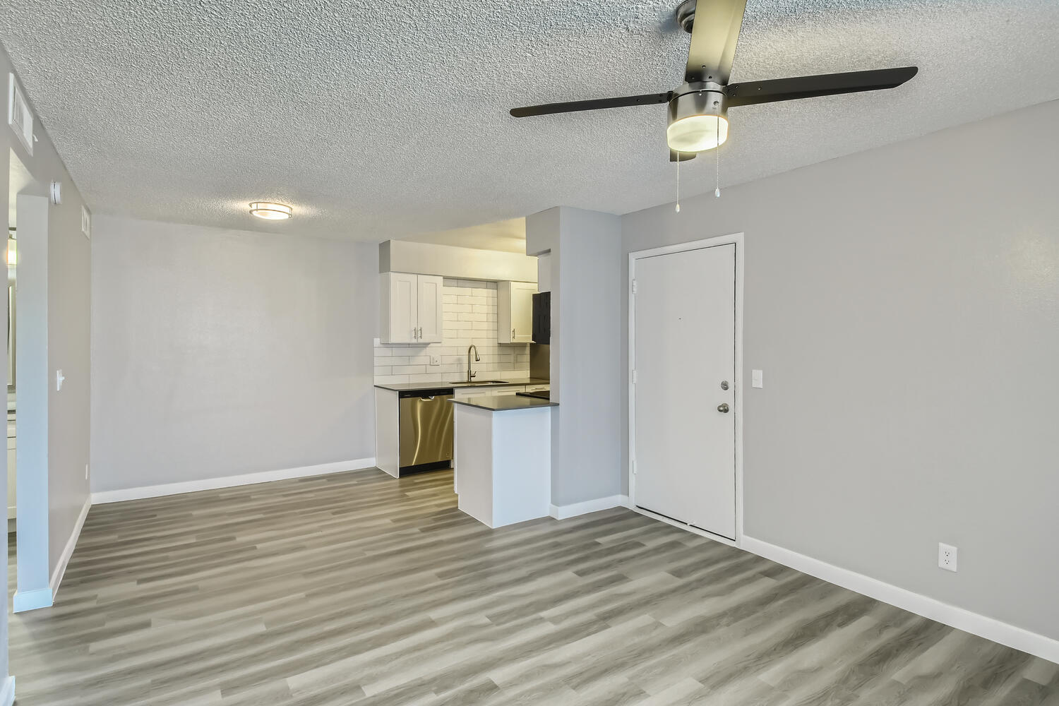 An open-concept apartment with wood-style floors and a dining and kitchen area at Rise North Ridge.