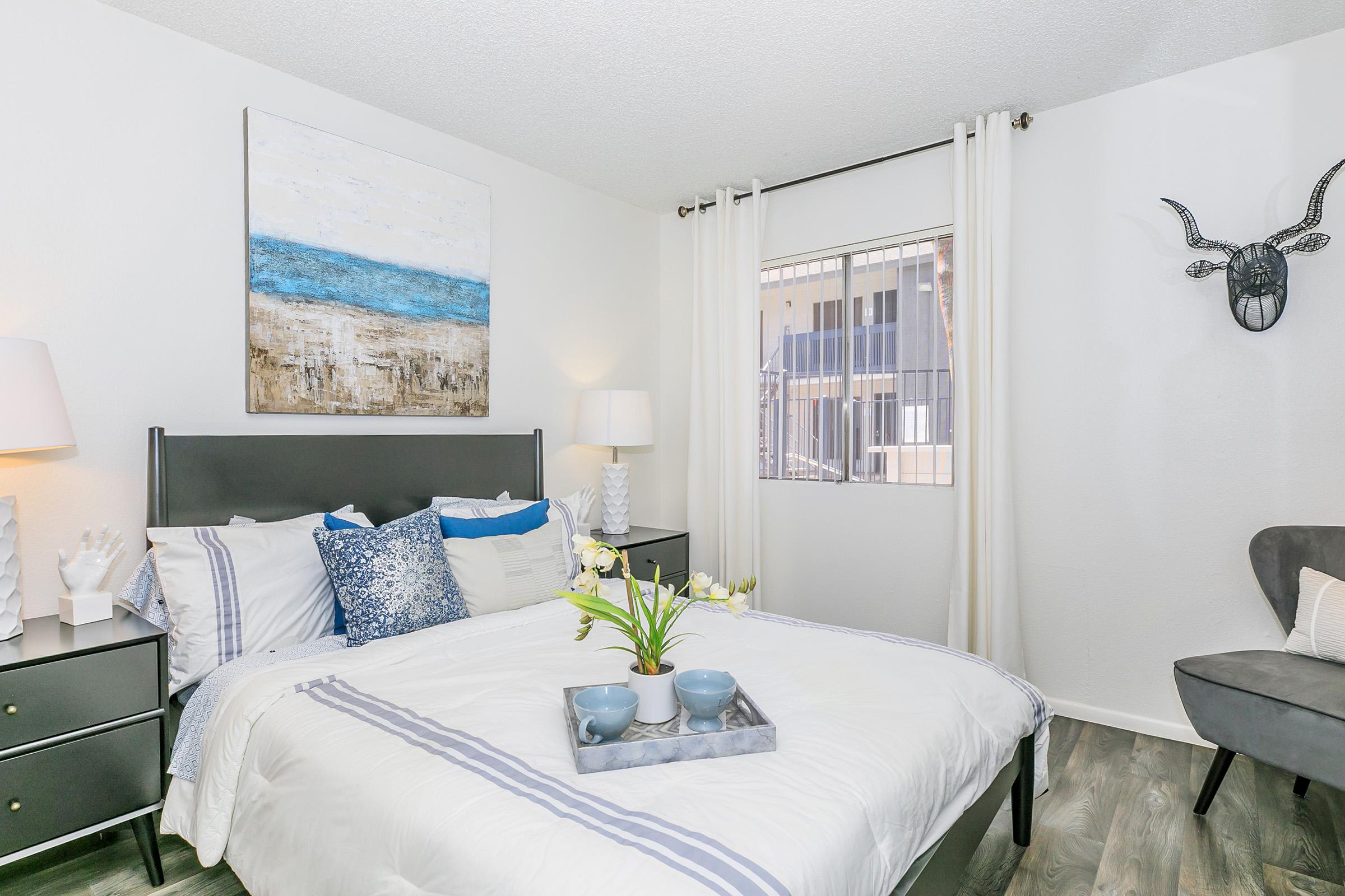 An apartment bedroom with a queen bed and a window at Rise North Ridge.