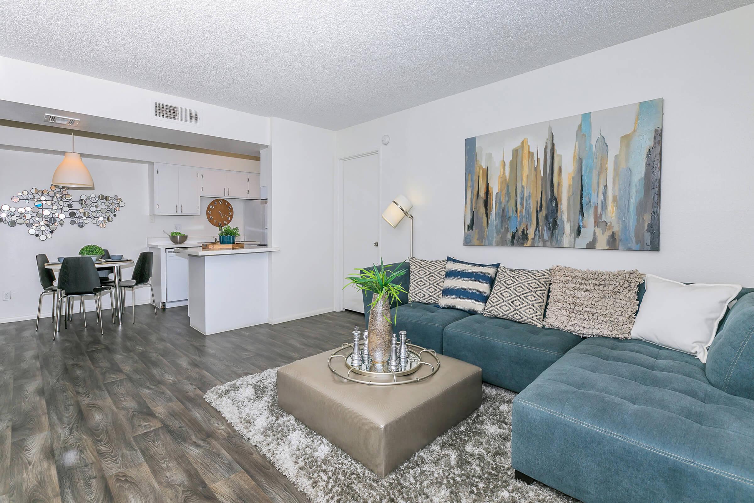 An apartment with a blue couch, a dining table and a kitchen at Rise North Ridge.