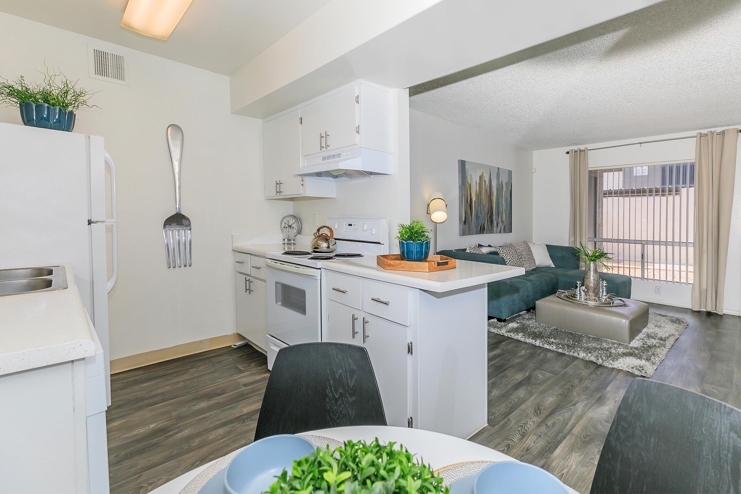 An open-concept floor plan with furniture in the dining and living area and a kitchen with white appliances at Rise North Ridge.