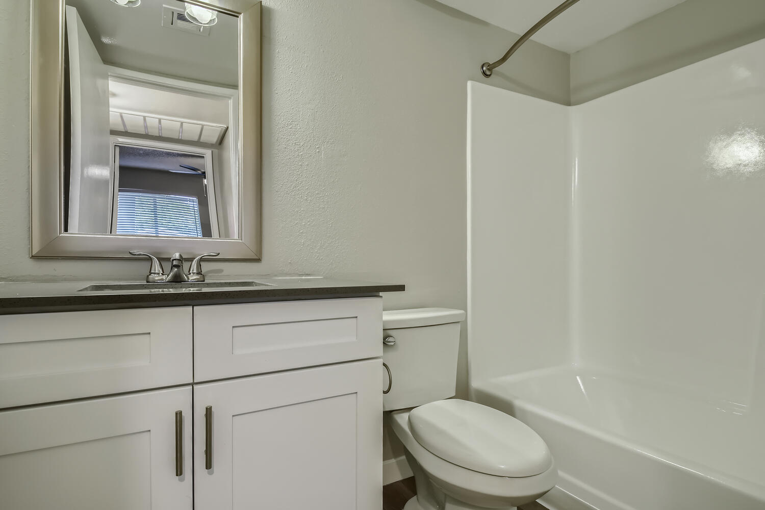 A bathroom with a vanity, mirror and a shower at Rise North Ridge.