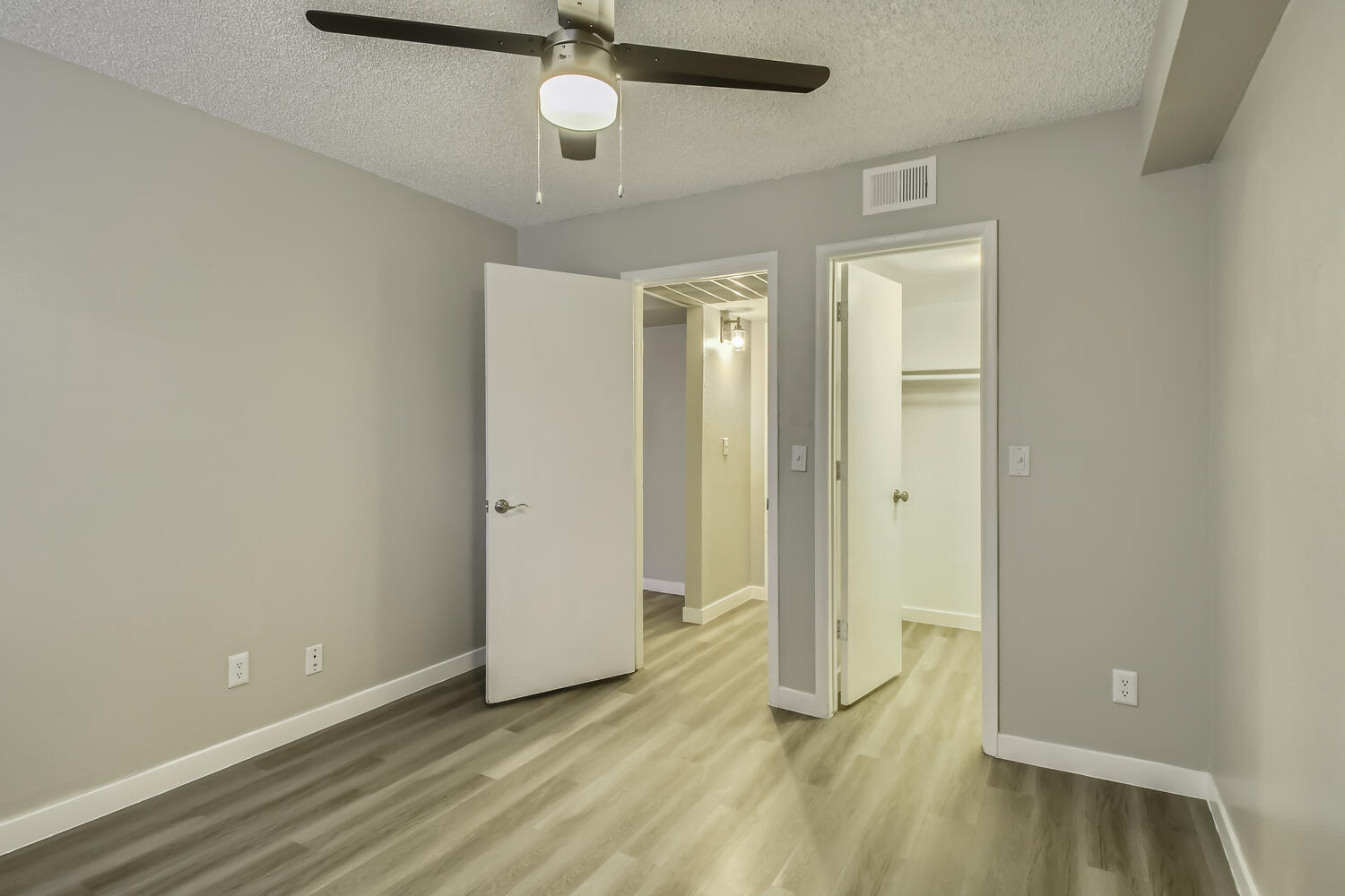 A bedroom with wood-style flooring and a closet at Rise Northridge.